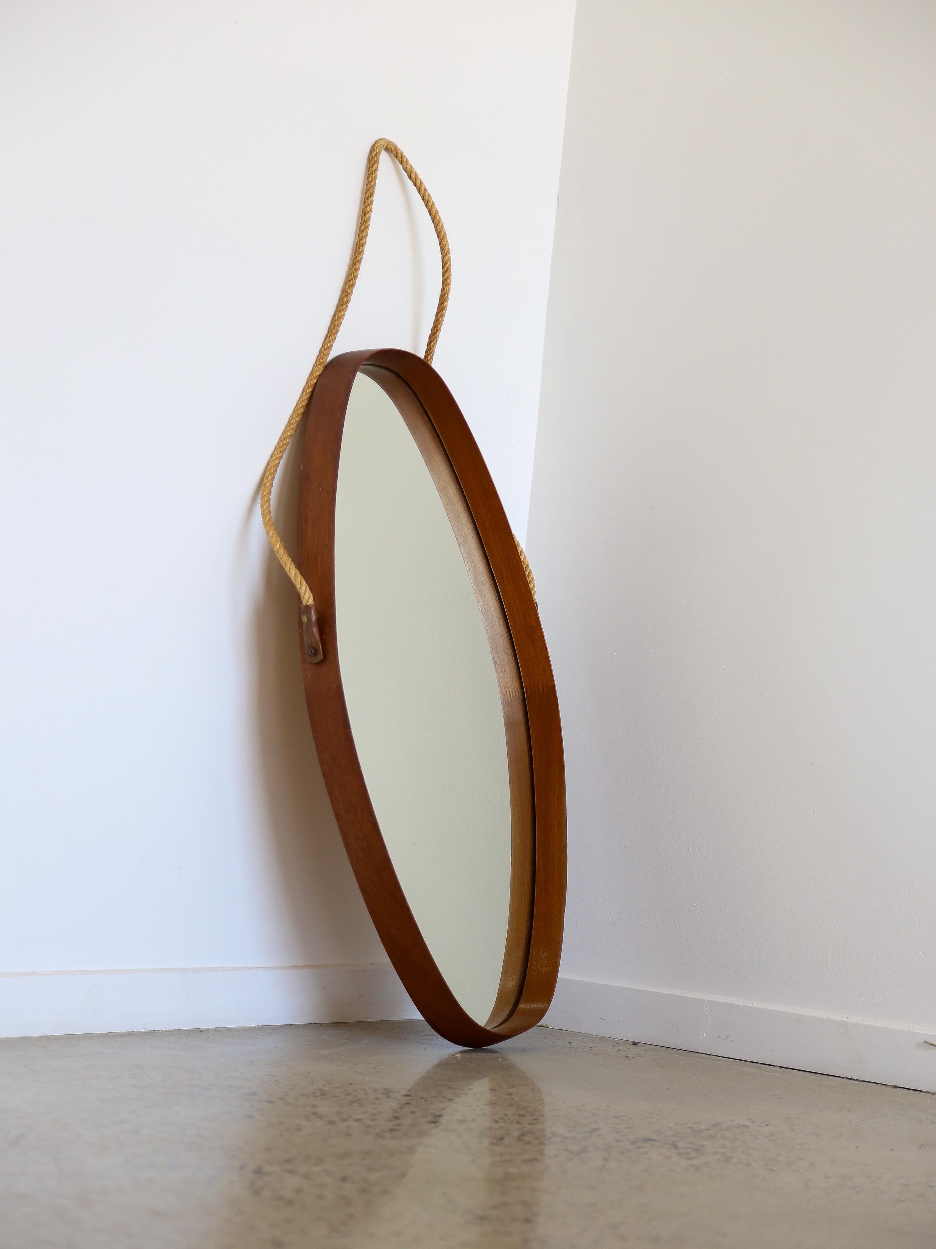 Italian Mid Century Modern round wall mirror.

The frame of the mirror is made from teak wood, which is known for its natural beauty and durability. Teakwood features a distinctive grain pattern and a warm, rich color that can add a touch of rustic