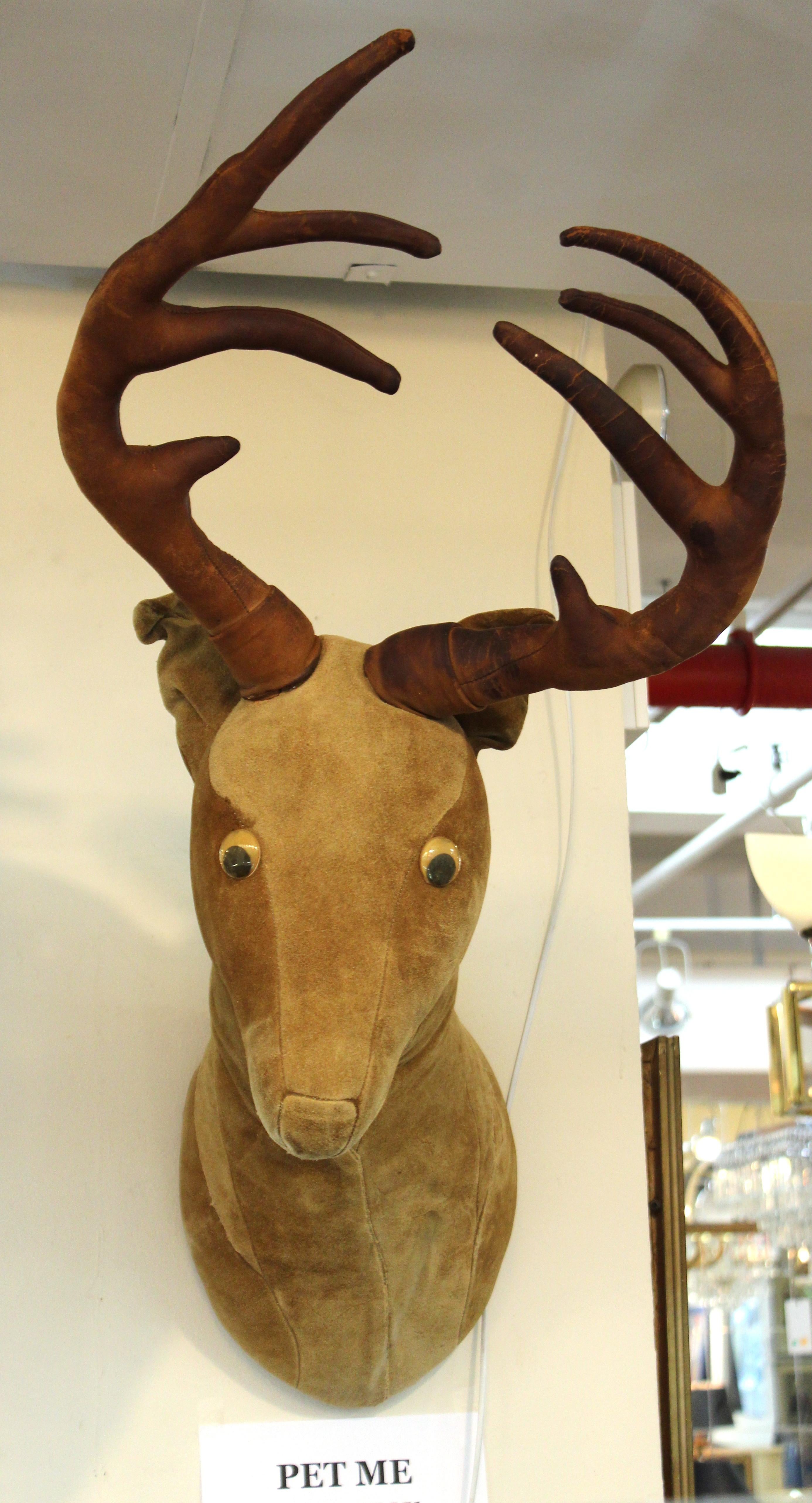 Mid-Century Modern wall-mounted deer head in leather upholstery with antlers and googly eyes. The piece is in great vintage condition with some age-appropriate wear to the leather surfaces and minor tarnish to the googly eyes.