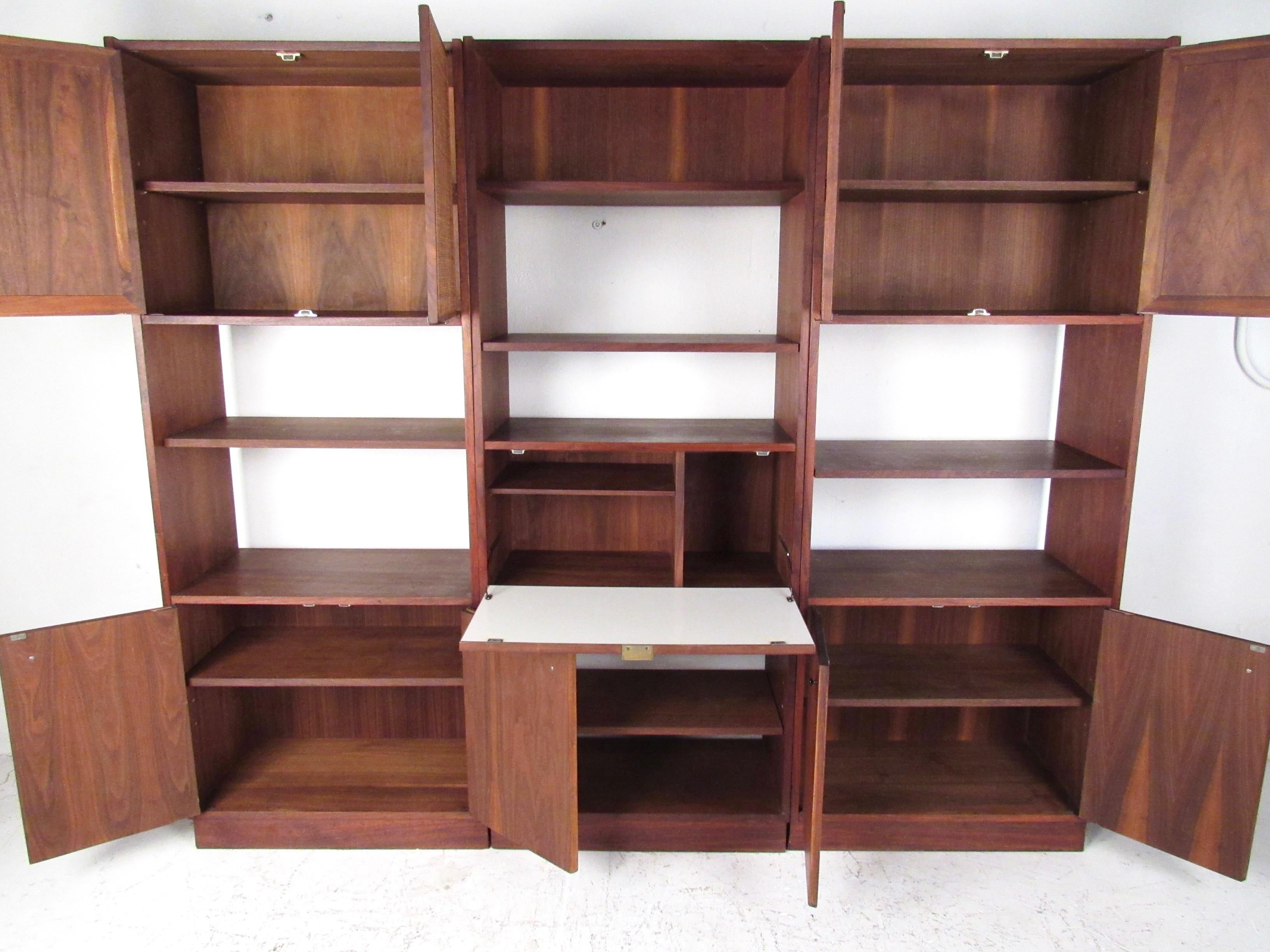 This stylish three-piece wall unit features Mid-Century Modern design and quality vintage construction. Cane front door panels add to the natural wood finish of the set and includes ample storage with open bookshelves and large cabinets, perfect for