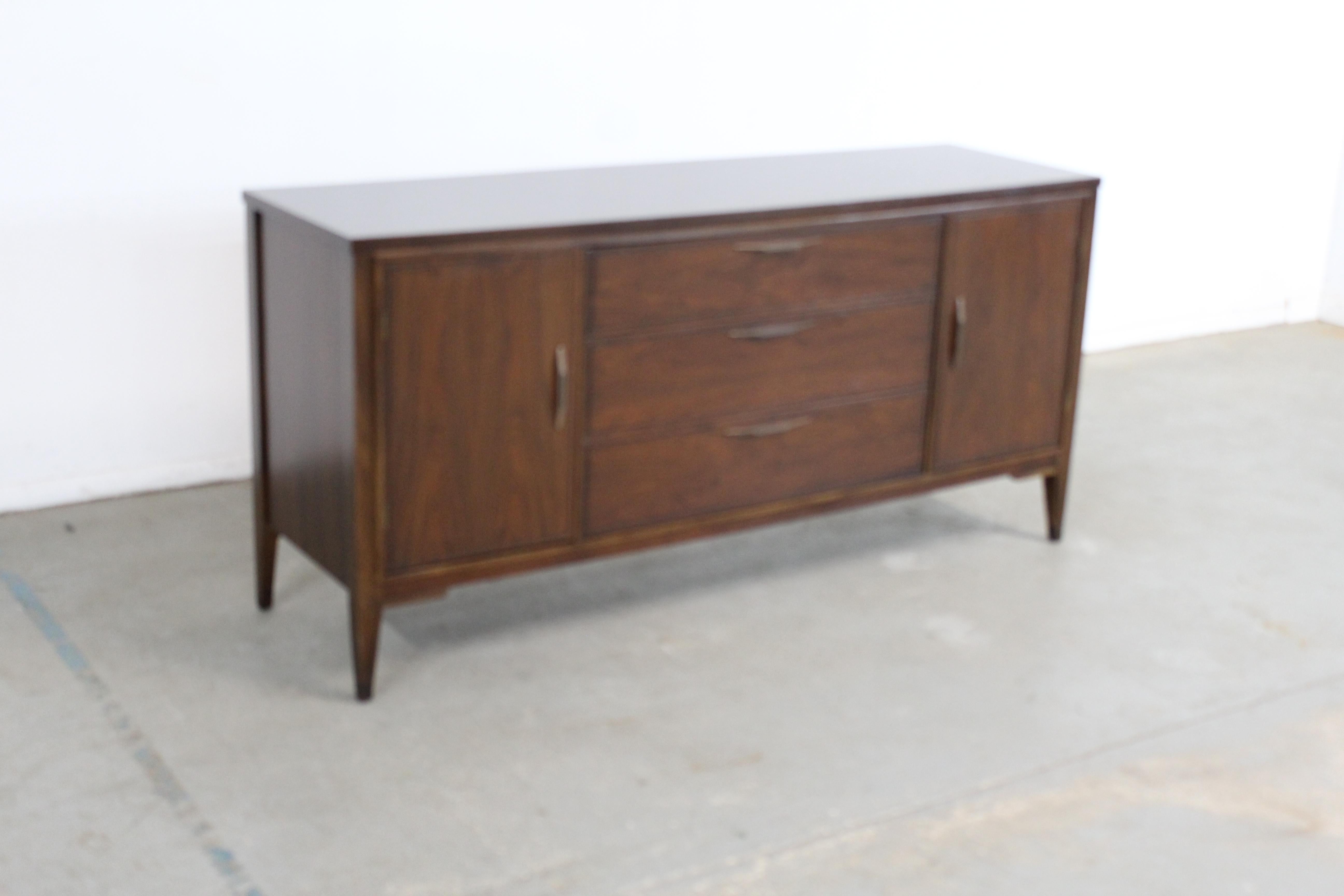Mid Century Modern Walnut 2 Door Credenza/Sideboard by Broyhill

Offered is a beautiful Mid-Century Modern Walnut Credenza/Sideboard with ample storage space, which was designed by Broyhill. Features 3 drawers and 2 doors. The top shows like glass