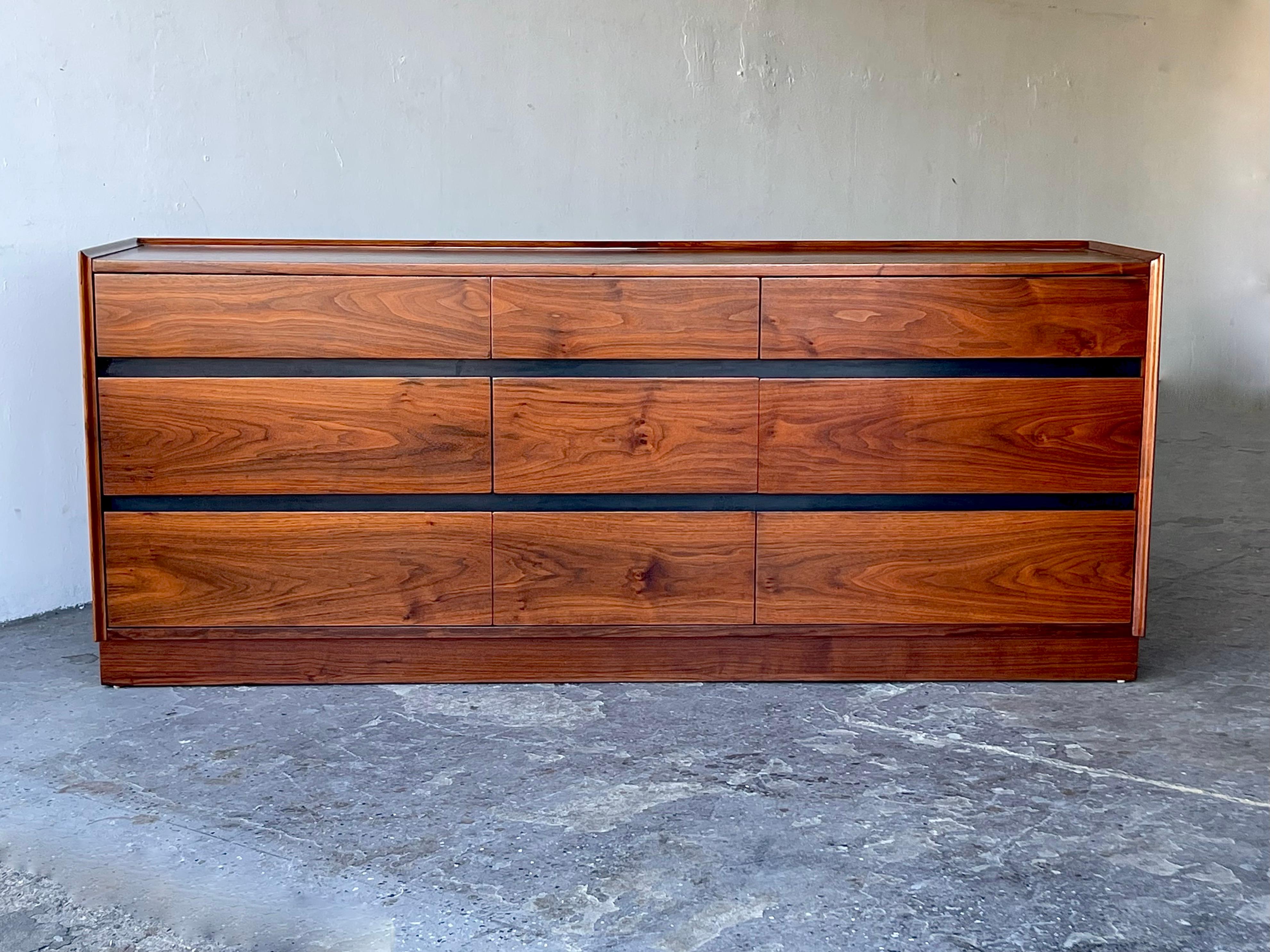 
 9-drawer chest with plinth base designed by Merton Gershun for Dillingham as part of the “Esprit” collection, circa 1960s. Handsome piece in walnut with original ebony trim with carved and beveled pulls to either the top or bottom of each drawer