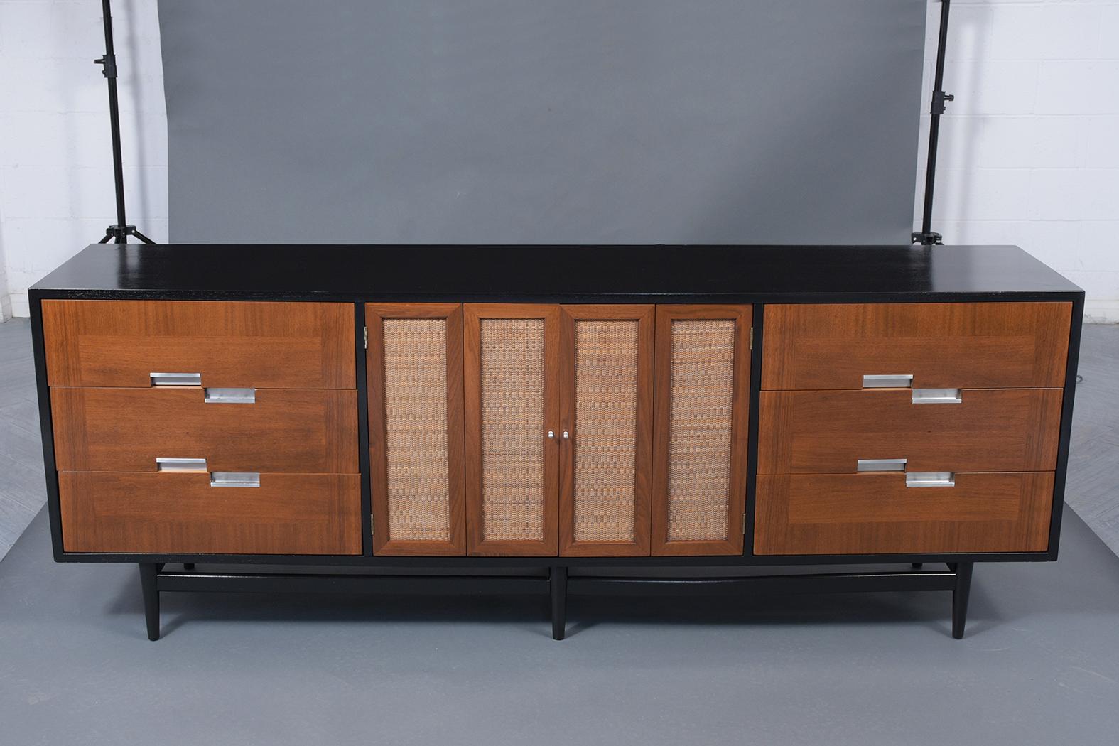 A beautiful 1960's modern credenza that has been professionally restored is made out of walnut wood and features a new ebonized & walnut color combination with a lacquer finish. This Chest of drawers comes with six drawers with asymmetric aluminum