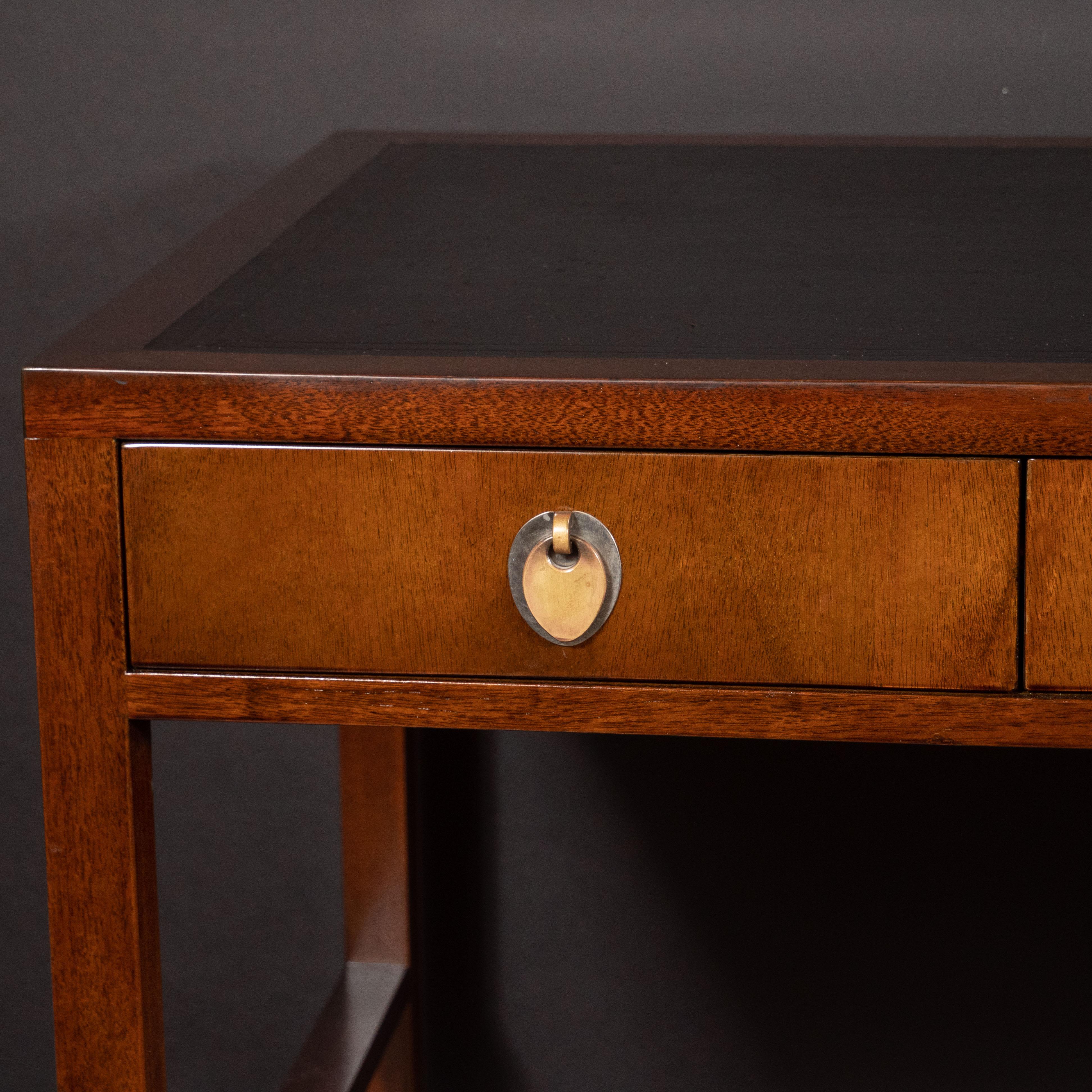 This elegant desk was created by the legendary midcentury designer Edward Wormley and handcrafted in Berne, Indiana, circa 1950. It features a rectangular body with the original inset black leather top that features banded detailing around its