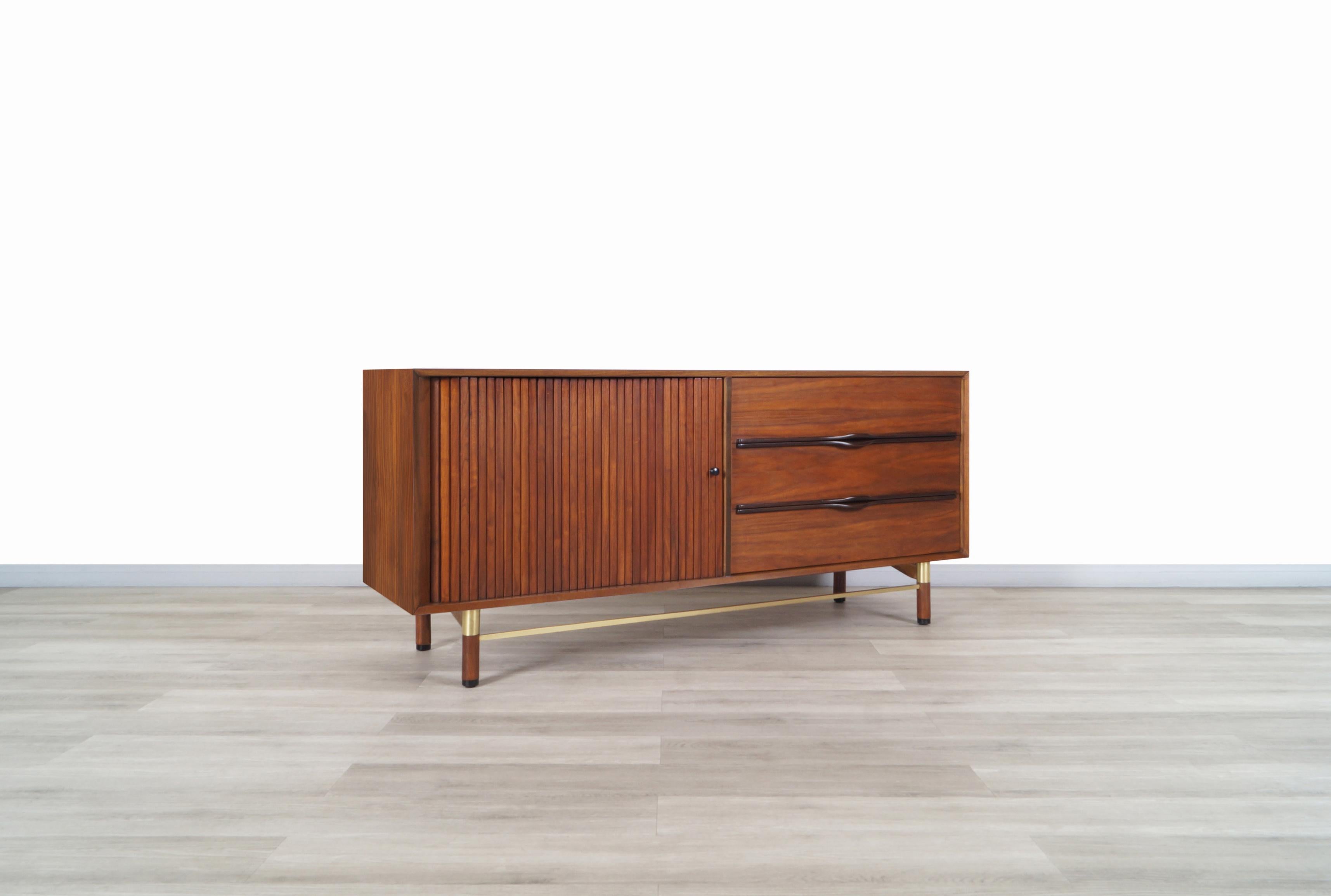 Beautiful mid century walnut and brass credenza / dresser designed and manufactured in the United States, circa 1960s. This dresser has a minimalist design, combined with its materials result in an elegant and functional dresser. On the left side,