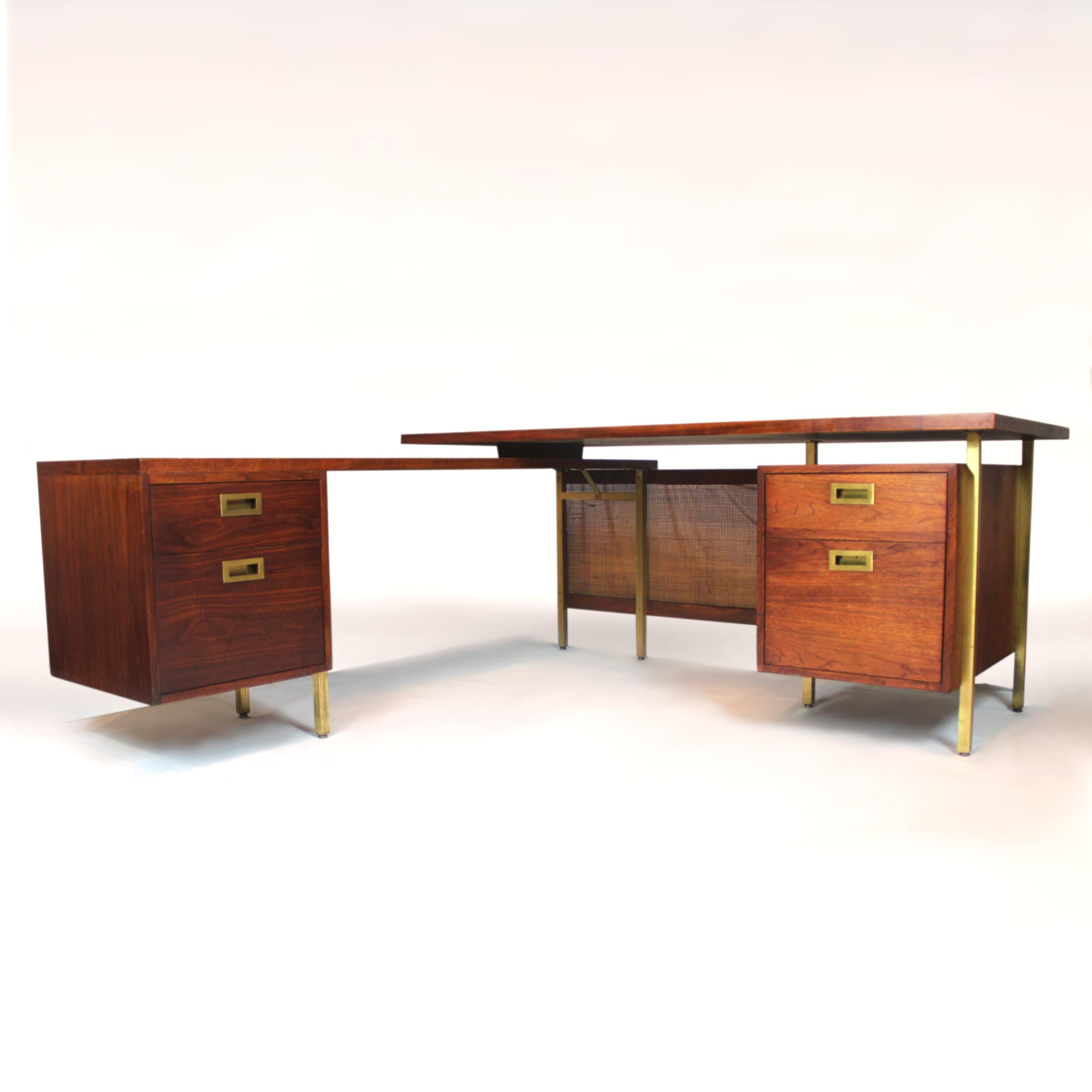 This gorgeous midcentury desk features book-matched walnut veneer, solid brass hardware, cast brass legs, cane modesty panel and solid walnut drawers. The floating top, stepped-down return and cantilevered cabinet give this desk a wonderful