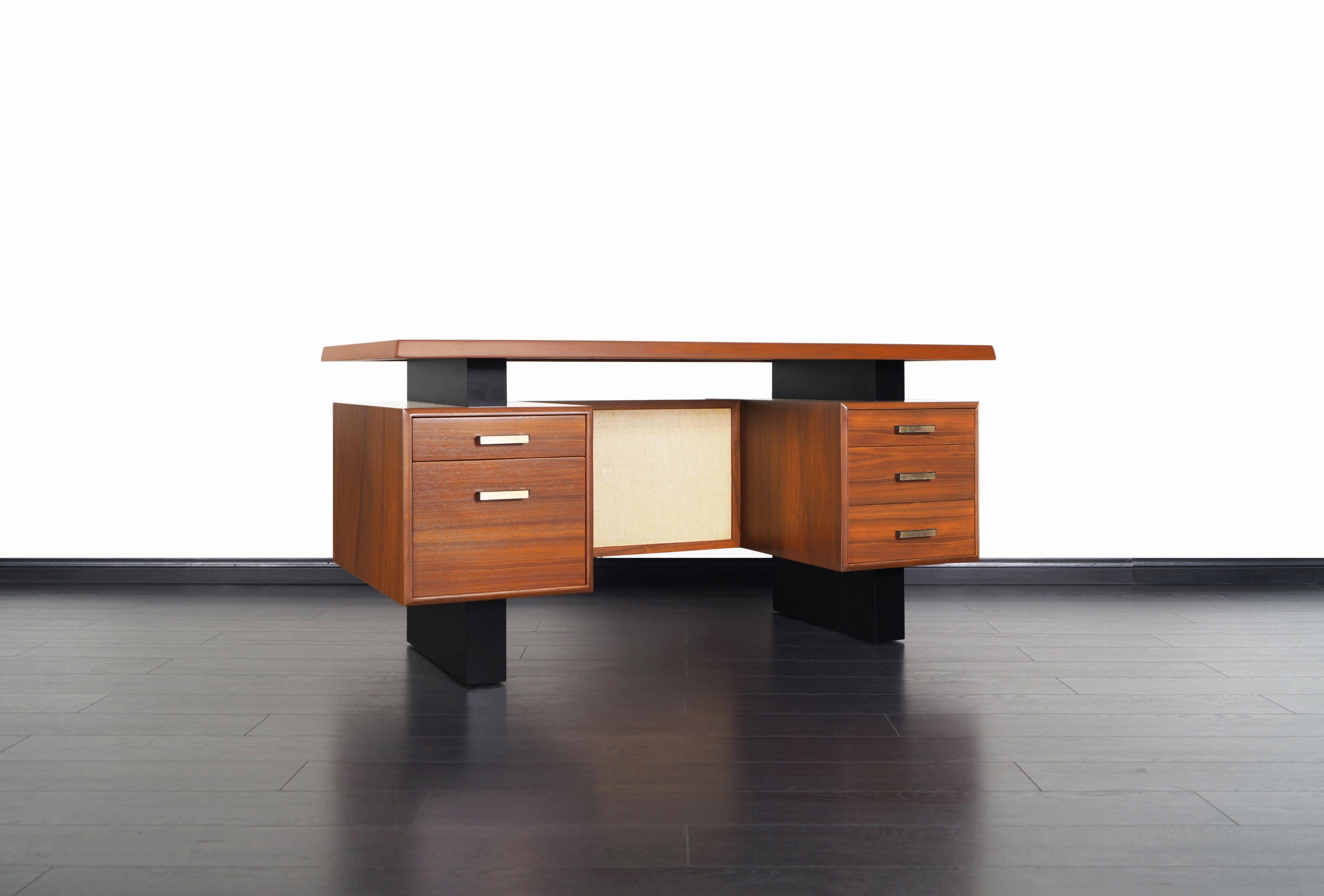 Beautiful midcentury walnut desk manufactured in the United States, circa 1960s. This design features a floating top with sculptured edges that sits over two sturdy walnut pedestal bases. Consist of a file drawer and four drawers. Both pedestal