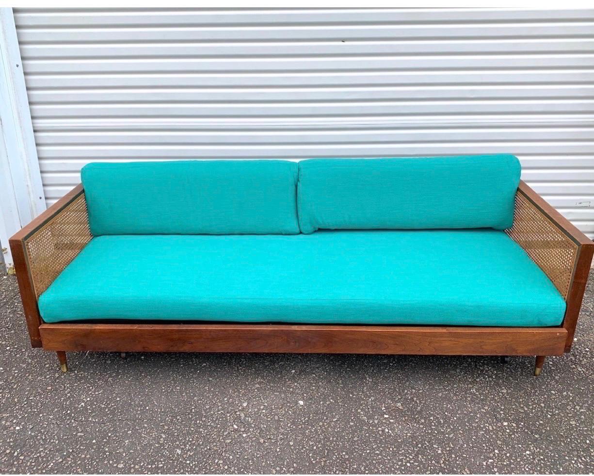 This sexy couch is in its original walnut and cane finish but has brand spanking new teal high performance sunbrela cushions. And it can also pop out to be a trundle bed, which is fully functional. The cane sides are free of holes and the upholstery