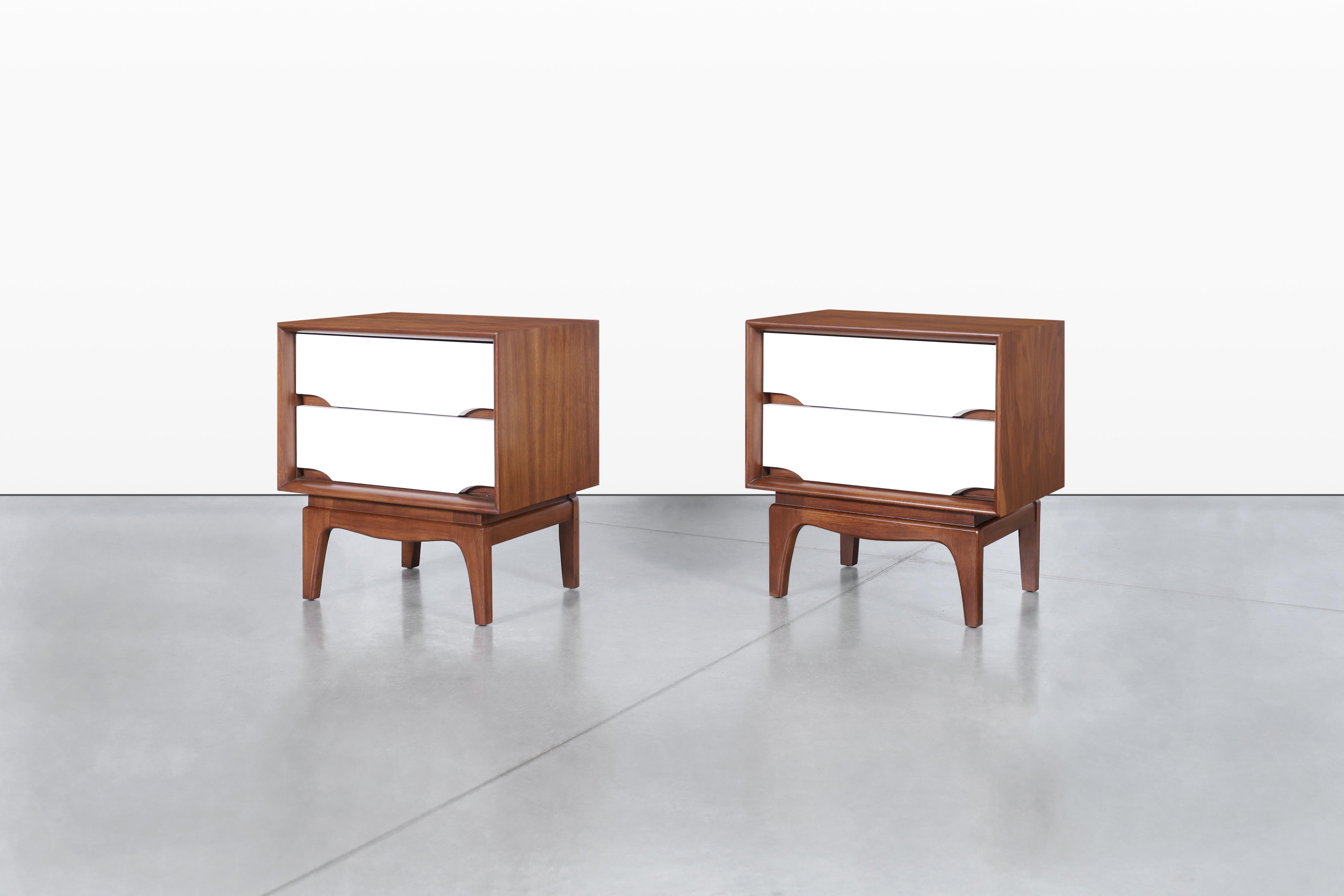 Imagina mejorar tu dormitorio con estas exquisitas mesillas de noche modernas de mediados de siglo de Kent Coffey, fabricadas en la década de 1950. Cada pieza luce una caja de nogal bellamente refinada que resalta con elegancia el rico veteado de la