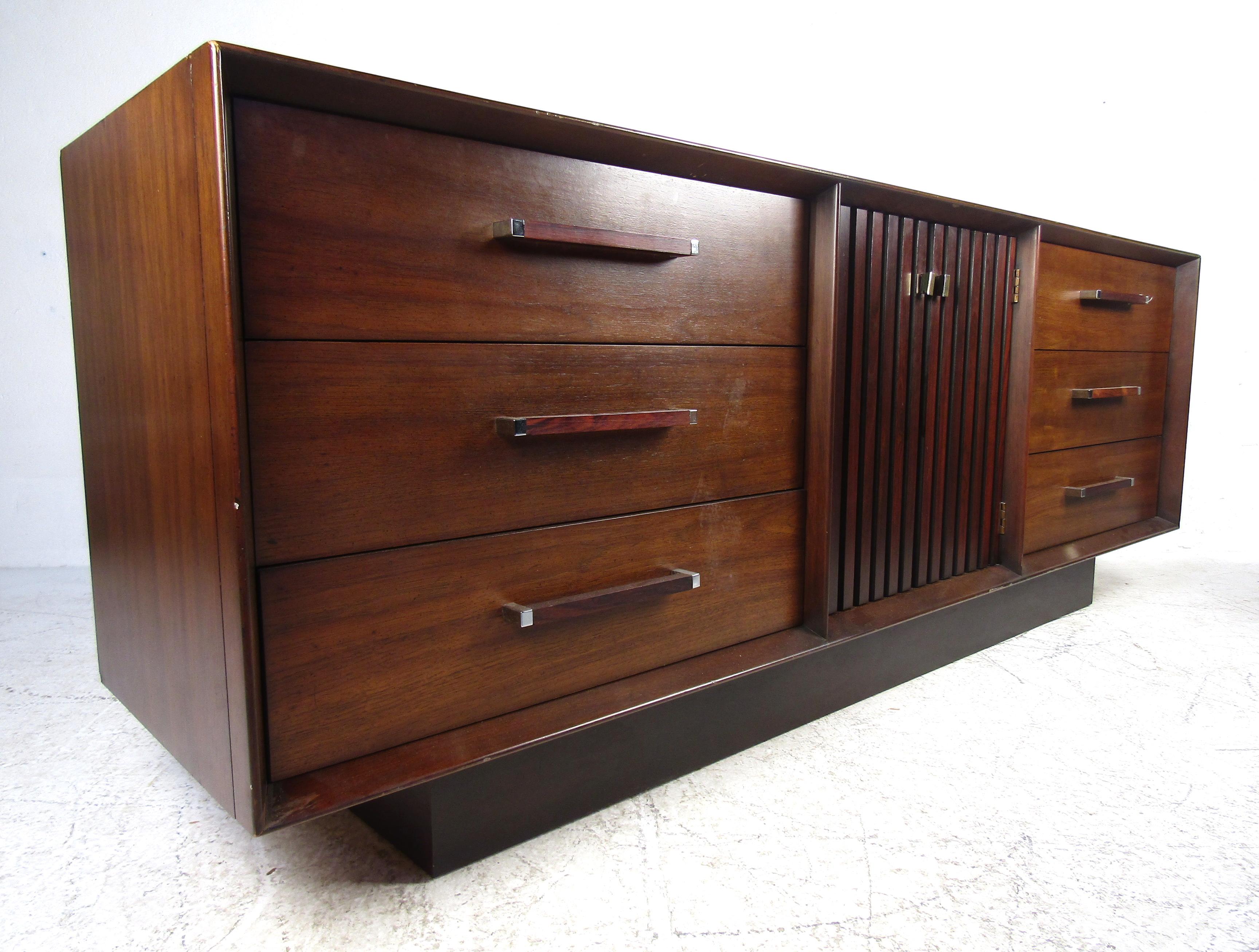 This beautiful vintage modern set includes two nightstands and a dresser. A lovely two-tone design with a walnut casing and rosewood accents/inlays. The unique rosewood and chrome drawer handles, vertical louvered cabinet doors and dovetailed
