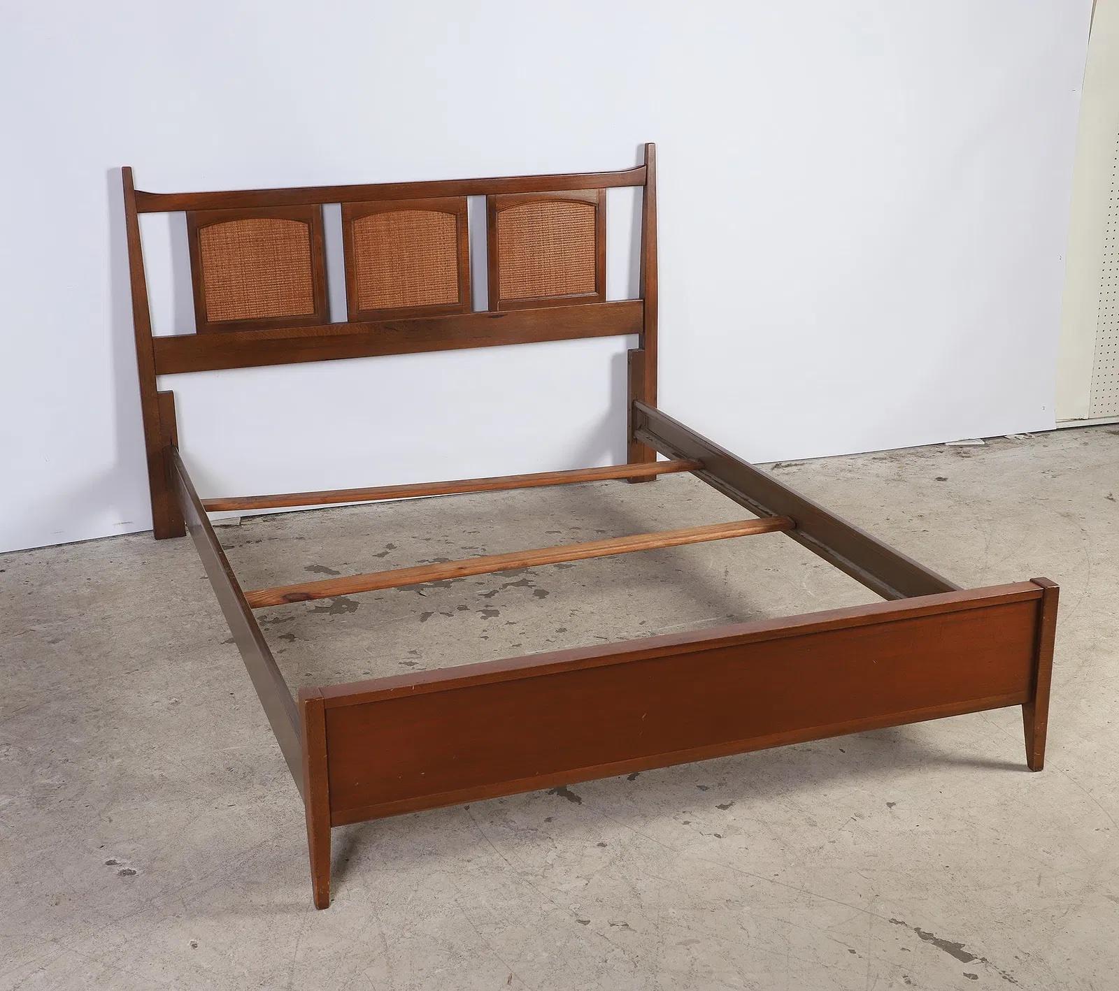 Full-size bed featuring a three-panel reeded headboard and a low footboard, typical of 1940s Colonial Revival design. The frame includes simulated woodgrain metal side rails and wood slats for support. 
