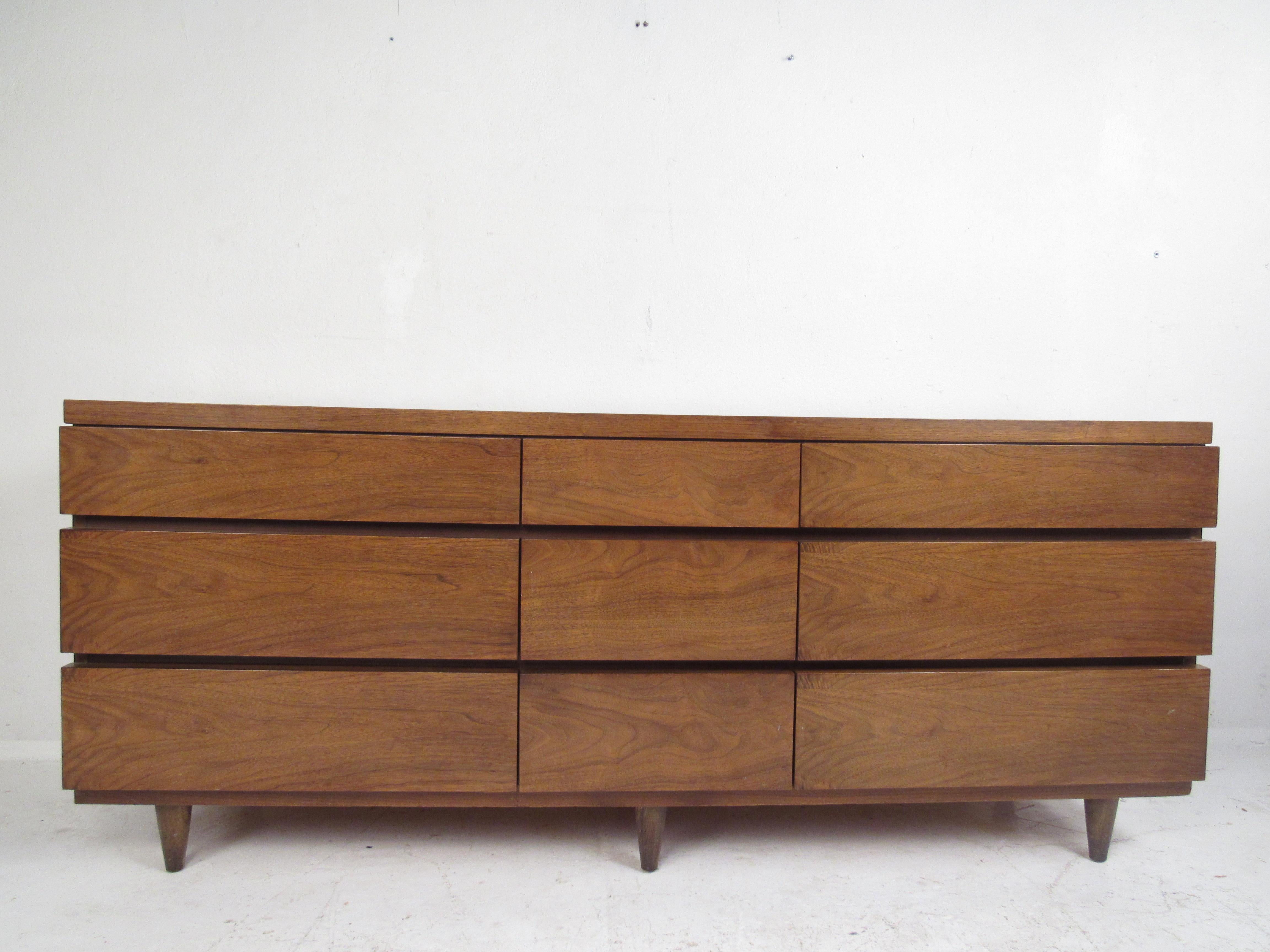 A beautiful vintage modern bedroom set that includes a low dresser and highboy dresser. This lovely bedroom set offers plenty of room for storage without sacrificing style. Quality craftsmanship with elegant walnut wood grain, hidden drawer pulls,