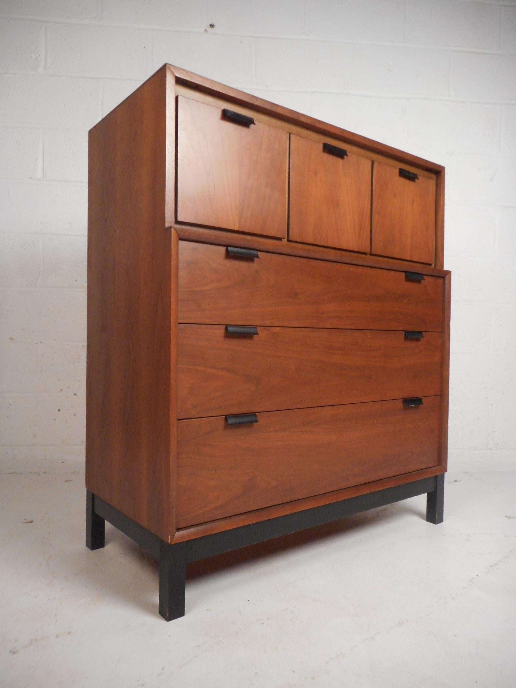 This beautiful vintage modern bedroom set includes a low dresser, a highboy dresser, and a one drawer nightstand with a compartment underneath. The highboy features three cube shaped drawers on the top and three hefty rectangular drawers underneath.