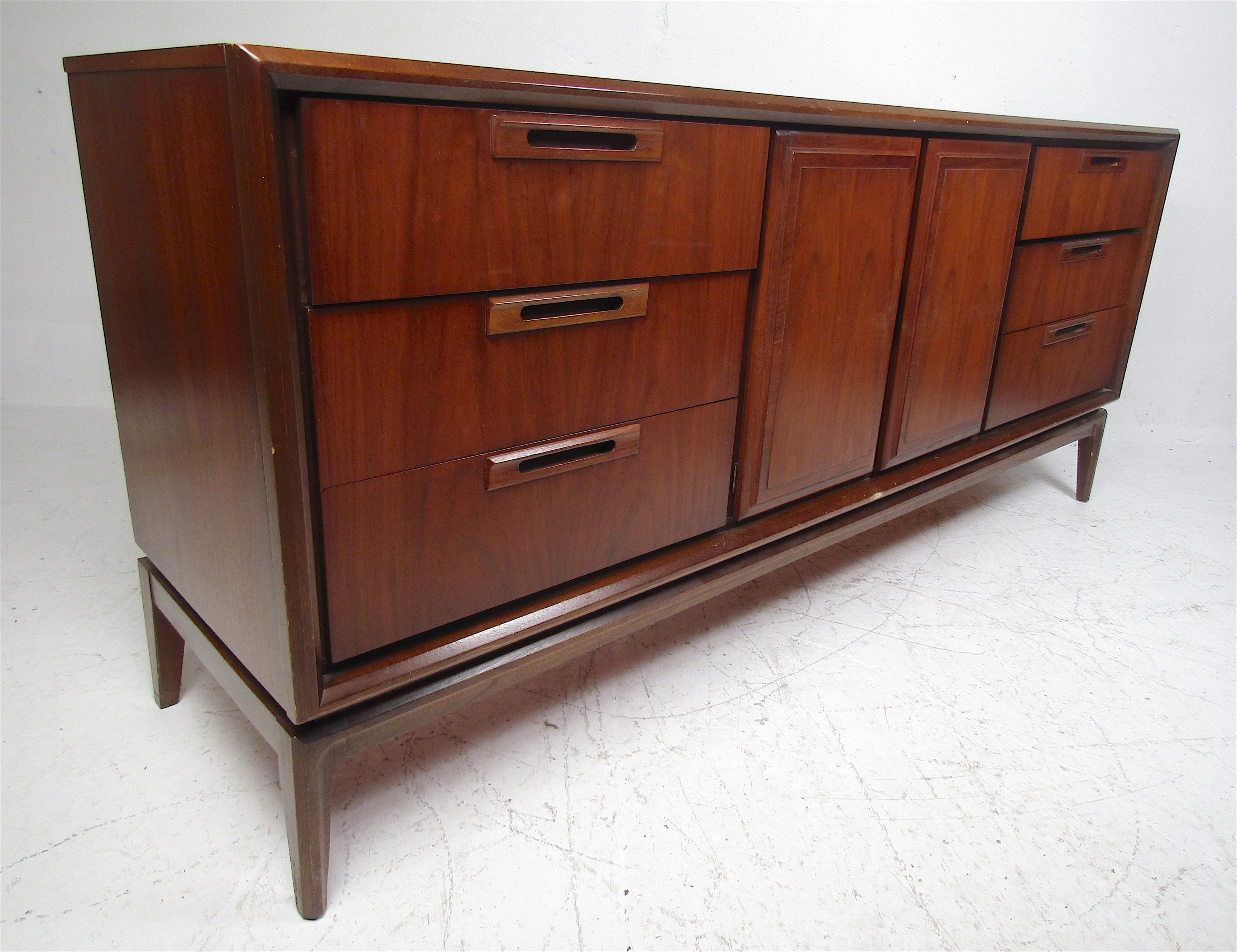This beautiful vintage modern bedroom set includes two nightstands, a highboy dresser, a lowboy dresser, and a queen size headboard. Sleek design with recessed drawer pulls, dovetailed drawers, and ample storage space. The headboard features a