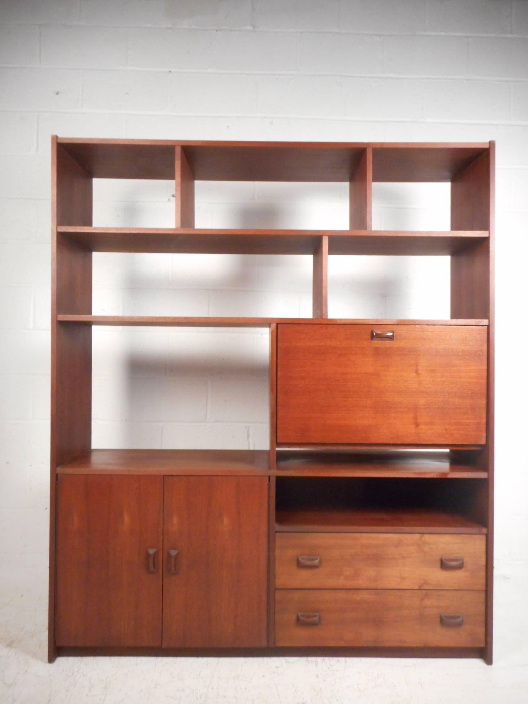 This gorgeous vintage modern room divider features plenty of room for storage and display. Wonderful design with numerous shelves, a drop front cabinet, two drawers and a storage compartment on the bottom. A versatile case piece with a finished back