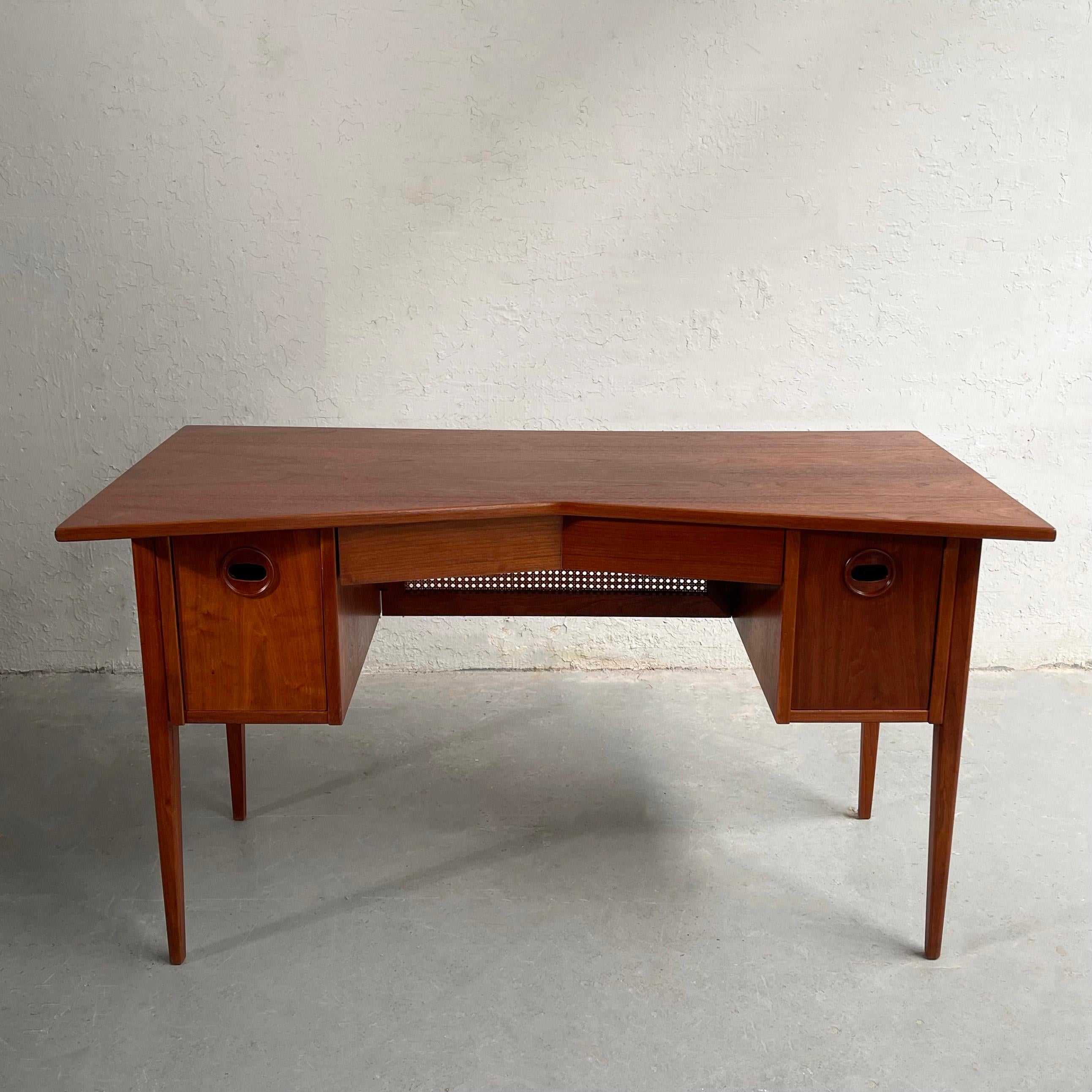 Outstanding, Mid-Century Modern, walnut desk features an angled bowtie top that tapers to 20 inches in the center with recessed drawer pulls and a caned privacy screen in front. The desk is finished on all sides.