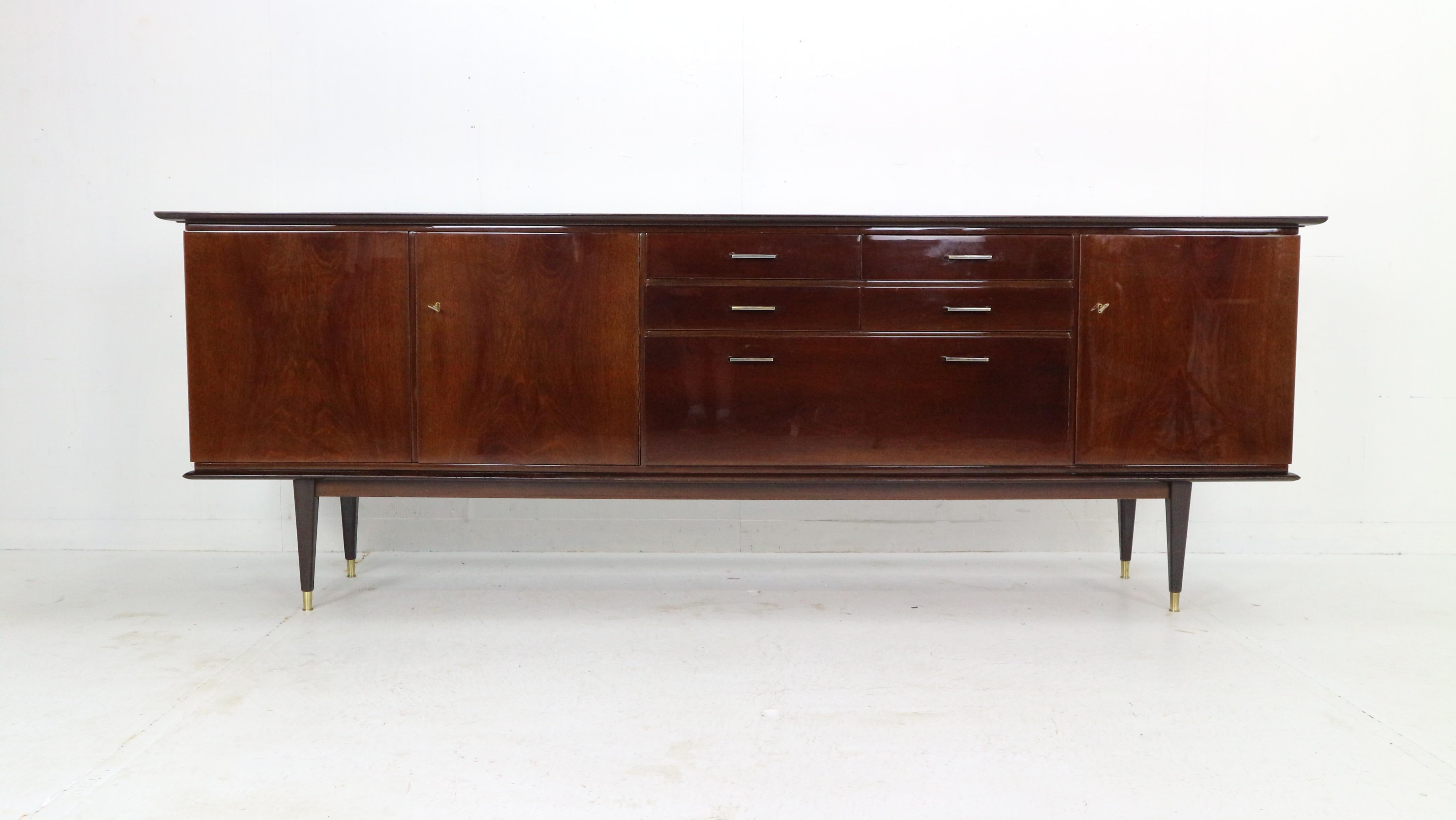 Magnificent Mid-Century Modern period sideboard produced in 1960's Denmark. 
Four drawers in the middle and shelving spaces from both sides with working locks& key.
The sideboard is made of walnut wood and has been lacquered which gives shinny