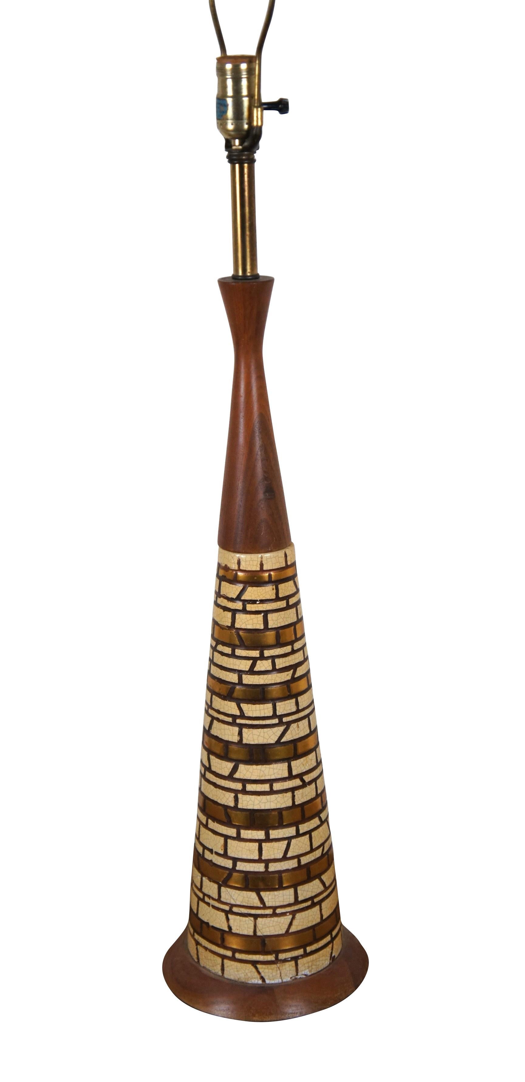 Tall mid 20th century circa 1960s table lamp. Conical walnut body embellished with bands of brass and off white ceramic tiles in a brick / stone wall patterned mosaic. Includes harp and cylindrical finial. F.A.I.P.

Dimensions:
7