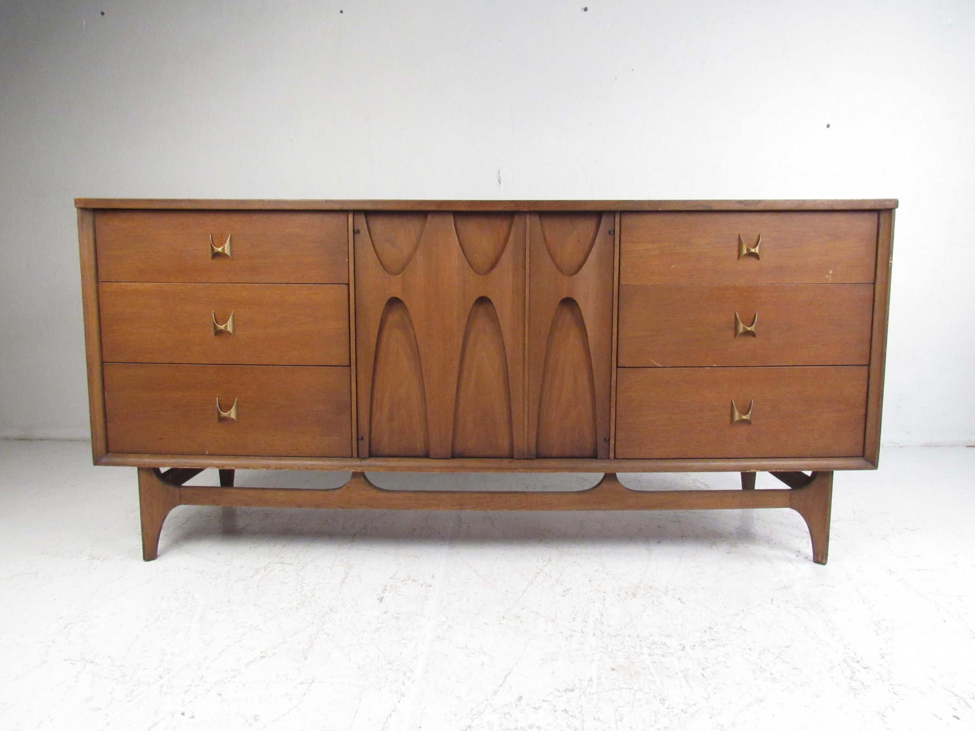 A beautiful vintage modern dresser by Broyhill Brasilia with nine hefty drawers. This stylish case piece boasts the iconic Brutalist cabinet door pulls and sculpted brass drawer pulls that Broyhill is known for. A sleek design with a vintage walnut