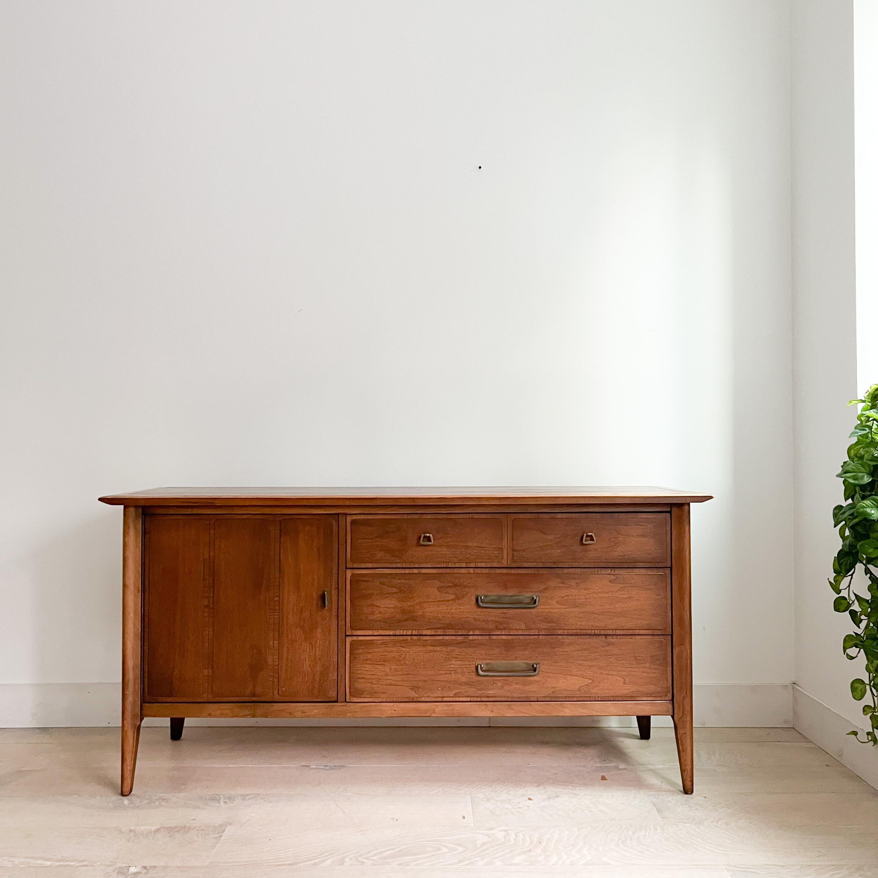 Discover the allure of mid-century modern design with this exquisite walnut buffet by Lane. Its top has been sanded and restored, revealing the rich, natural beauty of the walnut wood.

While this buffet showcases the elegance of mid-century style,