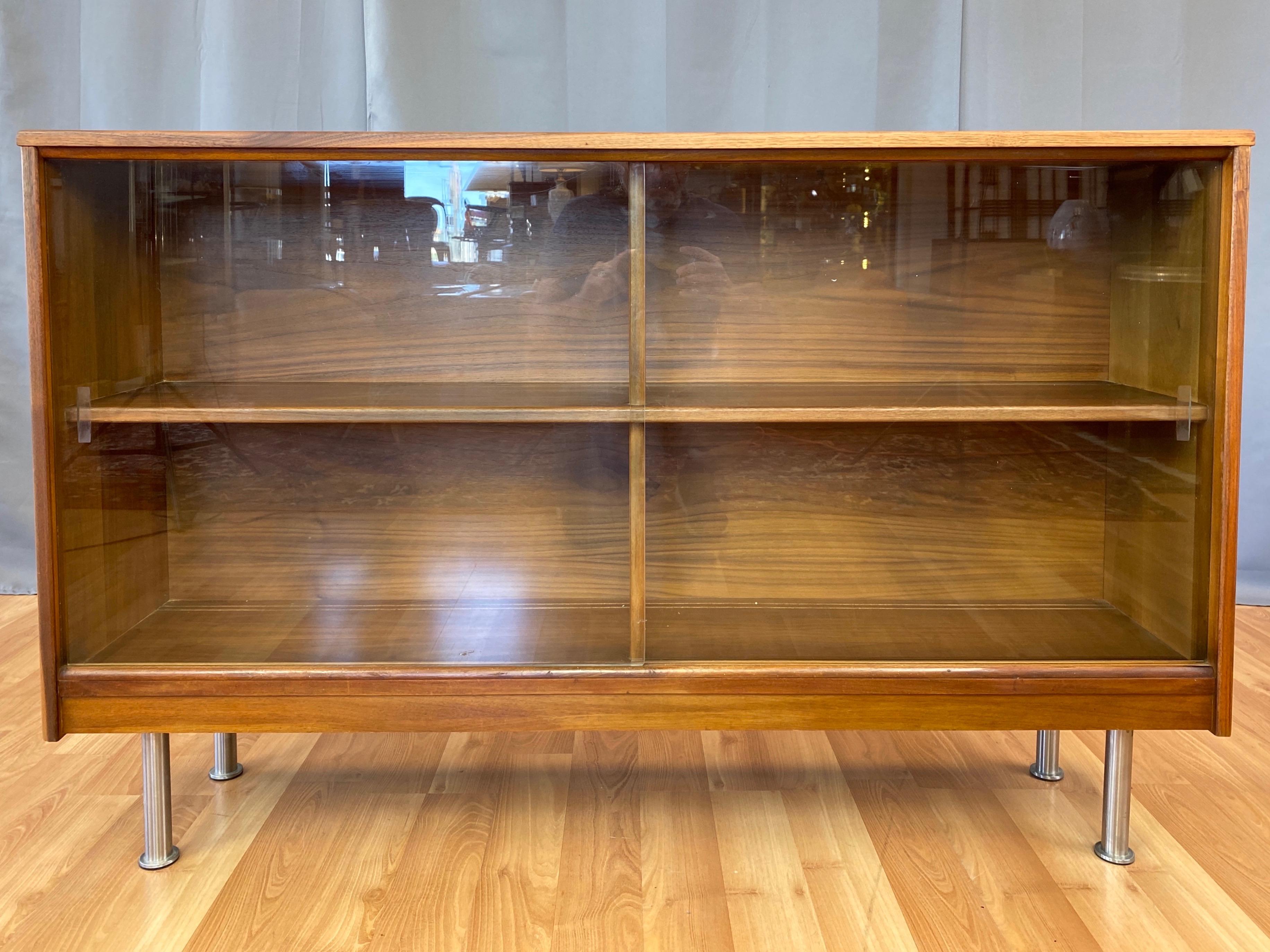 A spacious early 1960s mid-century modern walnut cabinet or bookcase with sliding glass door front.

Clean lines and handsome aesthetic would look equally great in a Danish modern or contemporary interior. Very well crafted, with nicely figured