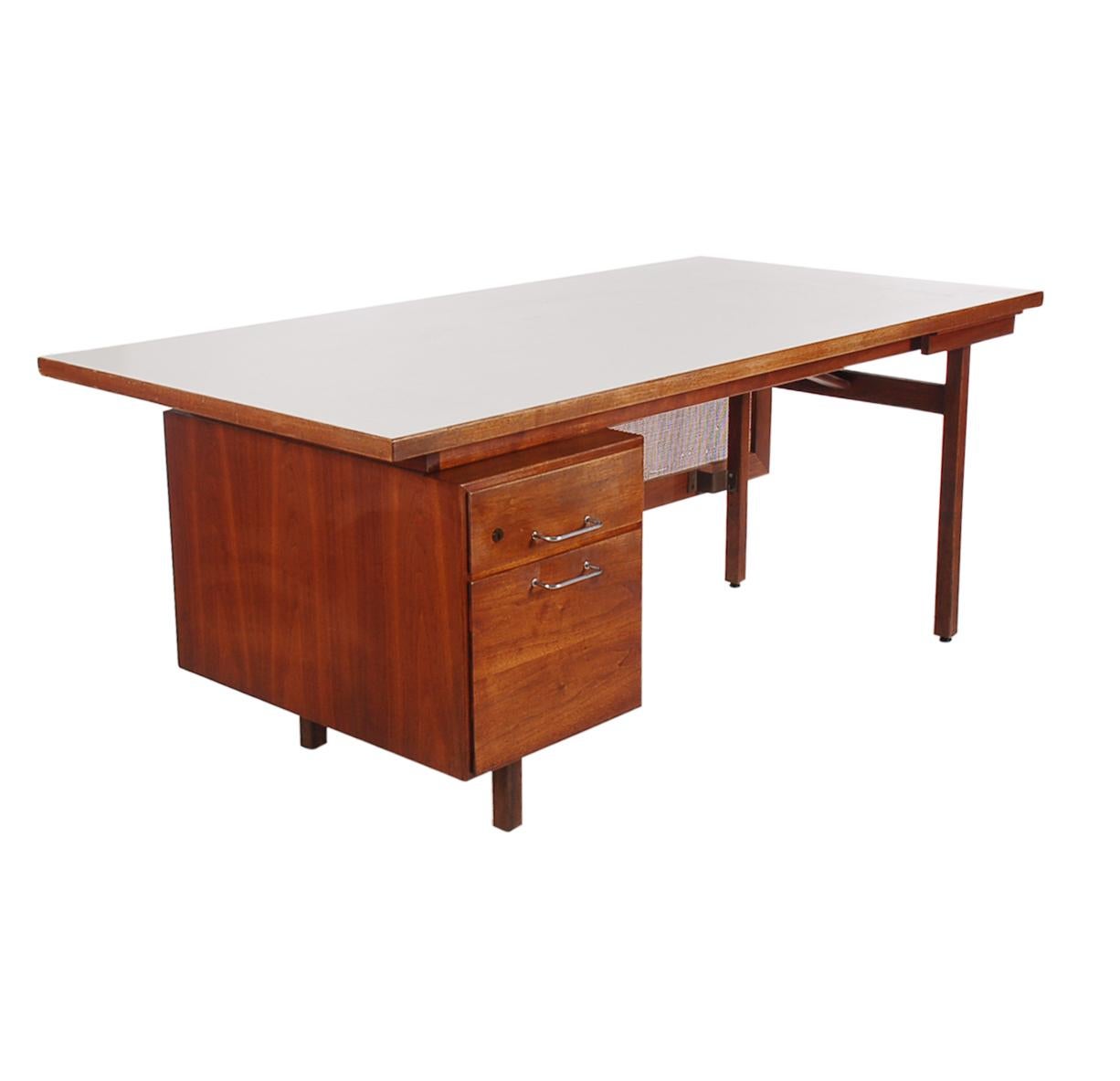 A substantial and sophisticated looking design by Jens Risom circa 1960s. This desk features solid walnut construction, white laminate top, and a floating front cane panel. In very clean condition and ready for immediate use.