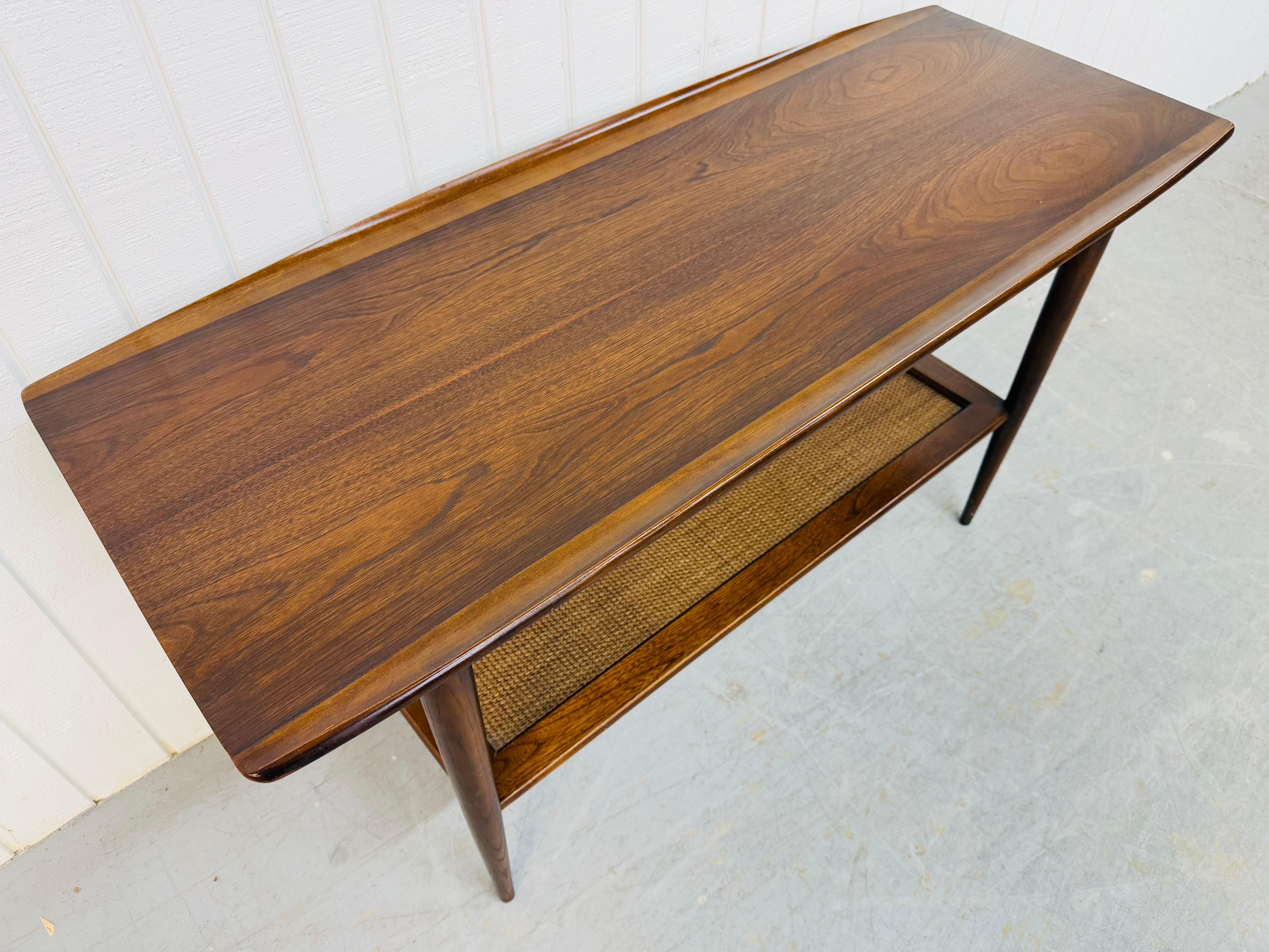 This listing is for a Mid-Century Modern Walnut & Cane Sofa Table. Featuring a straight line design, rectangular top with curved edges, long modern legs, bottom caned shelf, and a beautiful walnut finish. This is an exceptional combination of