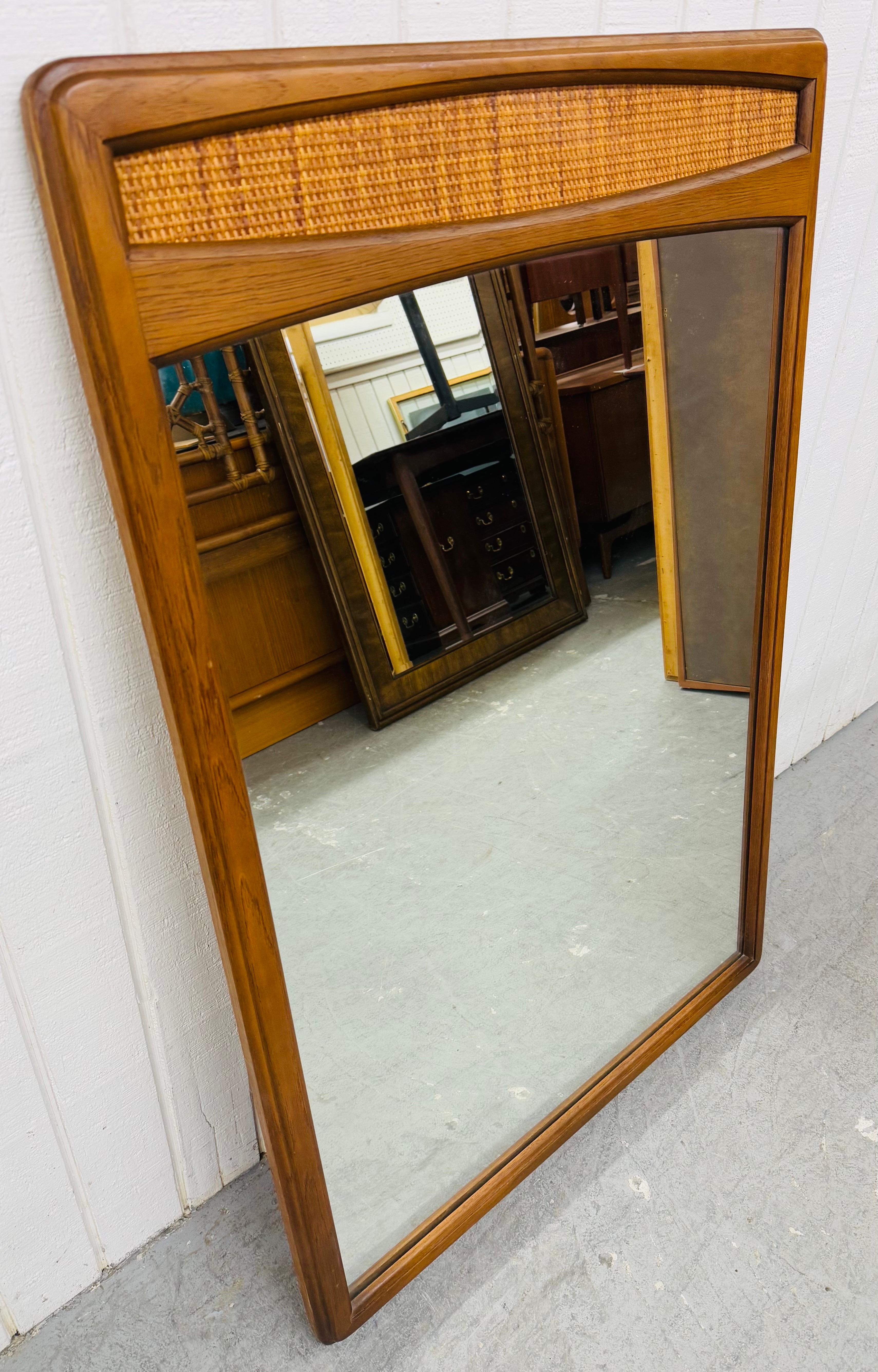 Cette annonce concerne un miroir mural en noyer et canne de style moderne du milieu du siècle. Elle se caractérise par un design rectiligne, un miroir rectangulaire, des accents en forme de canne et une magnifique finition en noyer. Il s'agit d'une