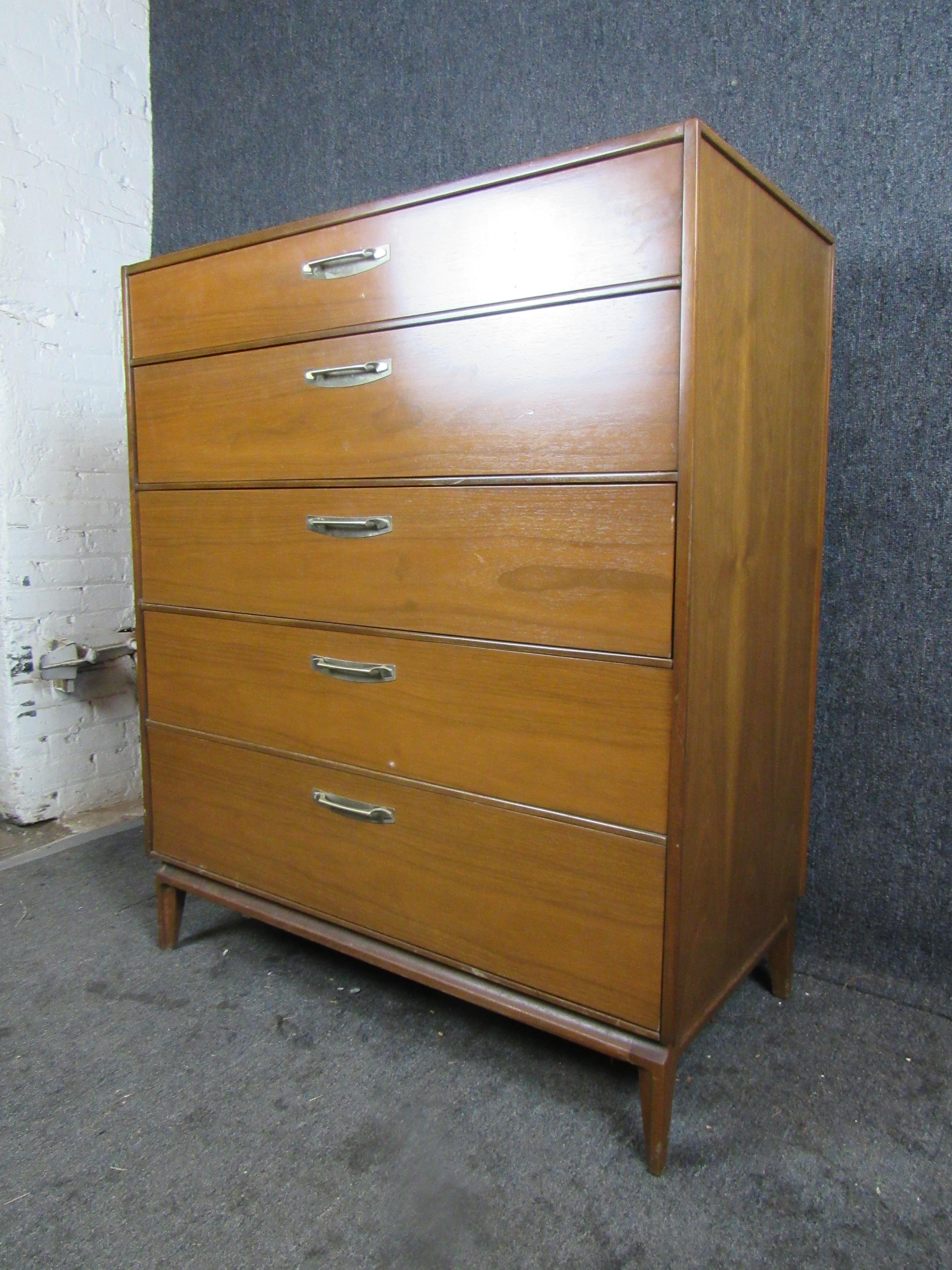 Gorgeous Mid-Century Modern vintage chest of drawers in a stunning walnut grain. Five pull-out drawers provide ample storage and organization, whether in the home or office. Unique metal pulls add a dramatic flair to the piece. 

