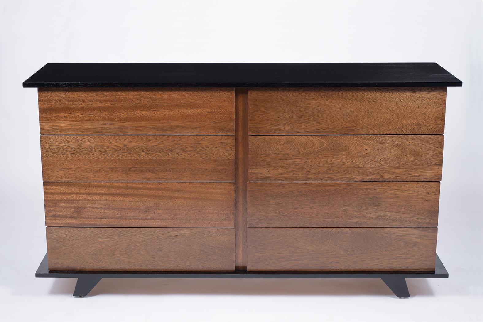 A sleek 1960's Modern Chest of Drawers handcrafted out of walnut wood features walnut stained drawers with an ebonized finish shell that wraps itself around the top and bottom of the piece. This piece comes with eight pullout drawers to open with