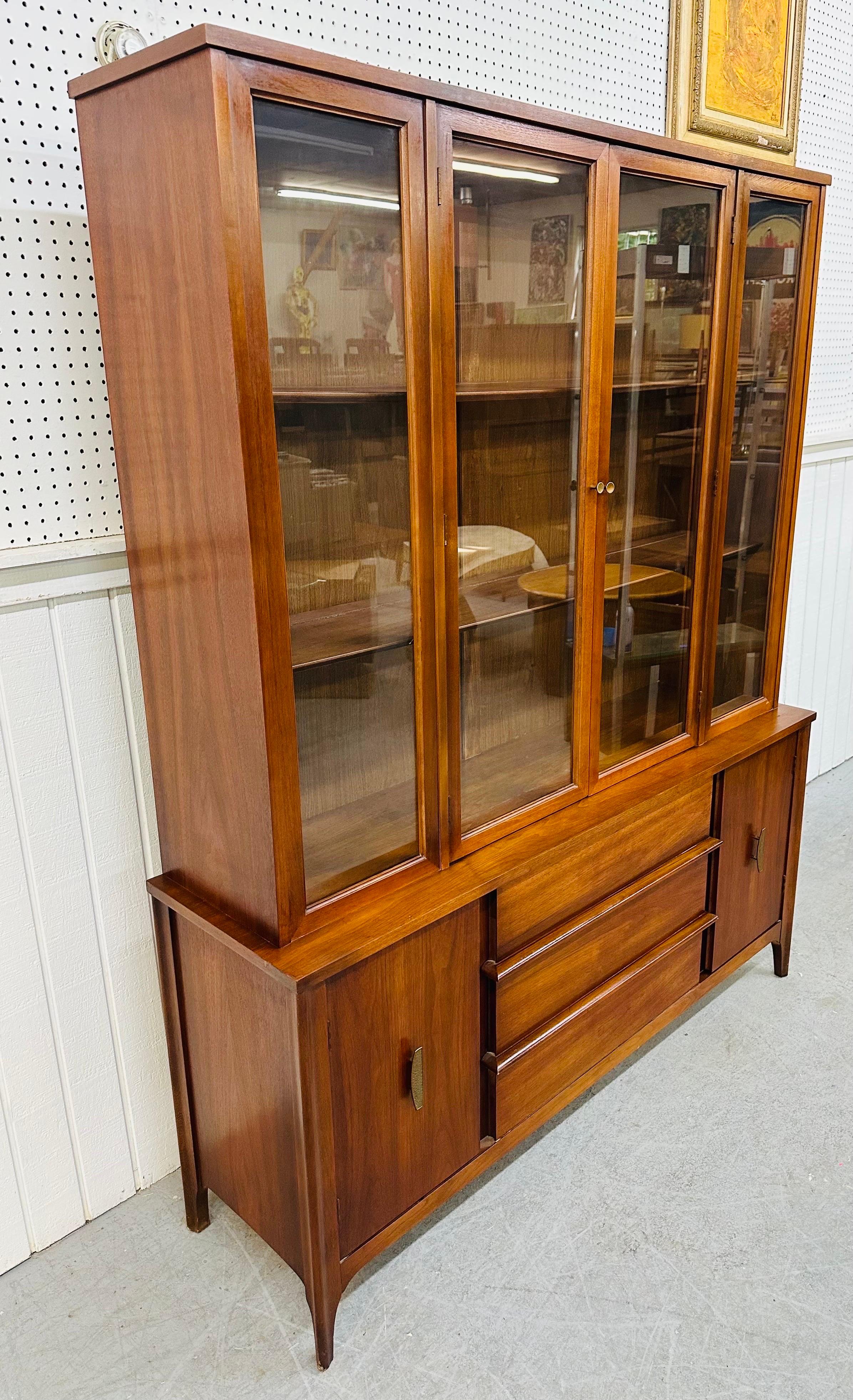 This listing is for a Mid-Century Modern Walnut China Cabinet. Featuring a straight line design, two doors that open up to shelving space, two doors with original hardware that open up to more storage space, three large center drawers, and a