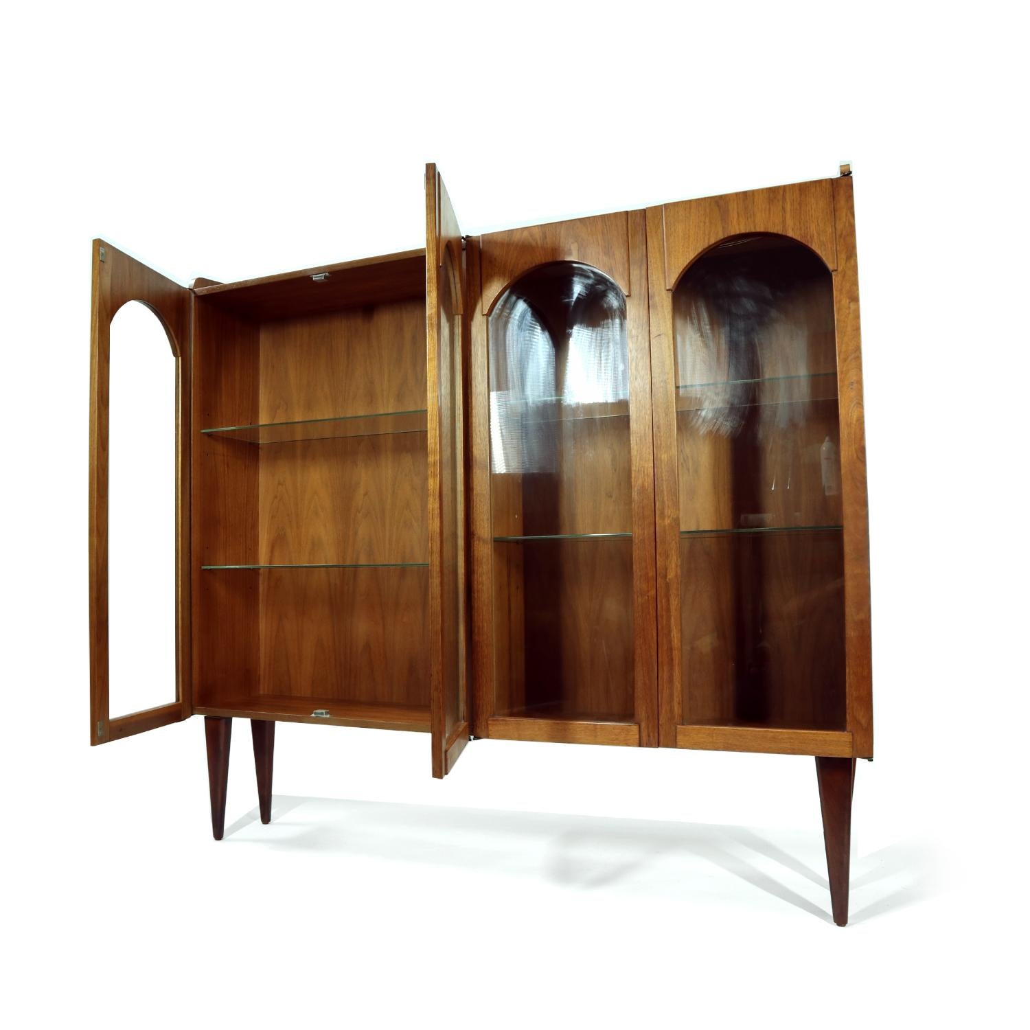 Handsome Mid-Century Modern walnut wood china cabinet with novel arched facade. This four bay china cabinet features four glass shelves inside. Reposition the shelves as you wish to create the perfect display for your cherished collectibles or