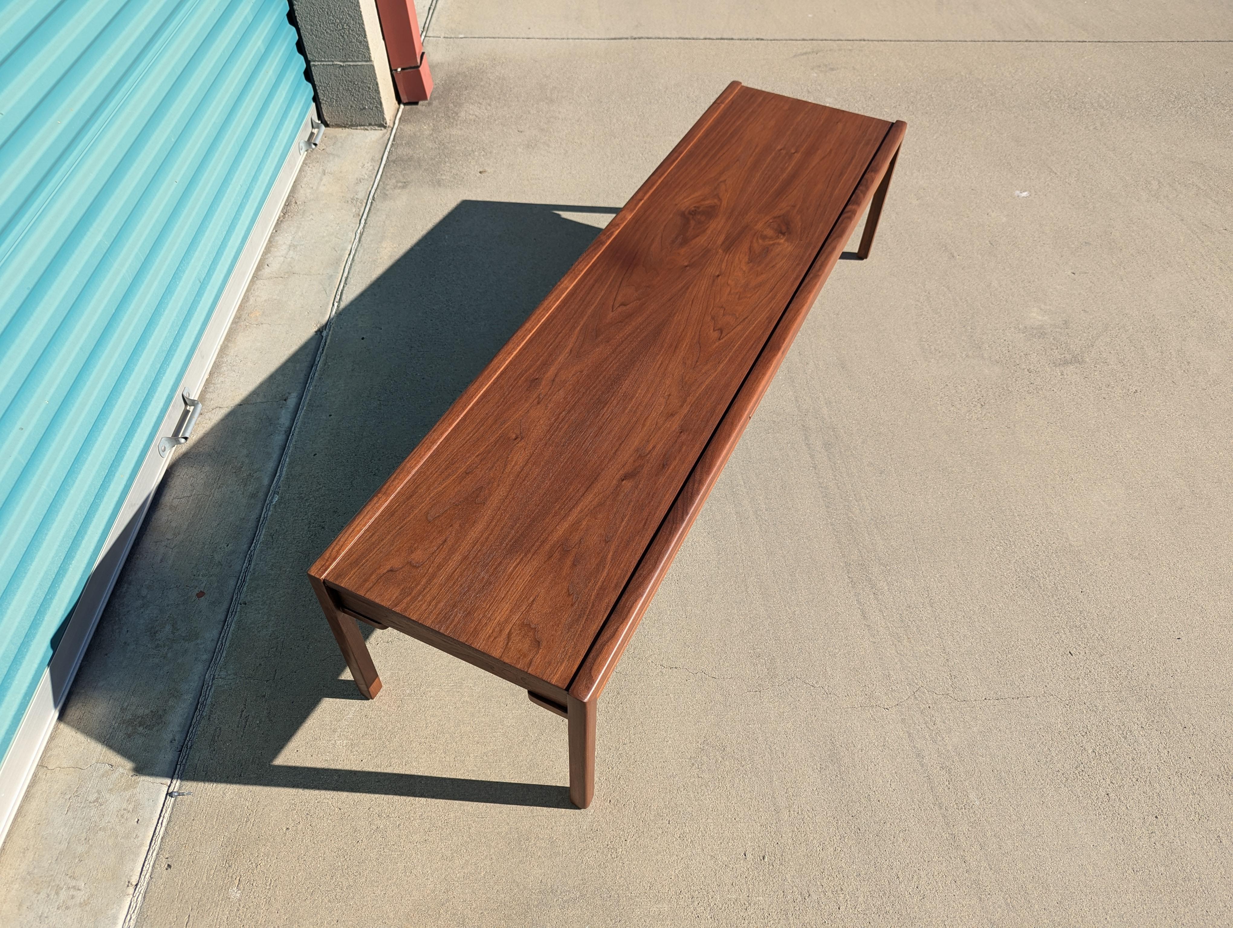 For sale is a stunning vintage mid-century modern walnut coffee table by the renowned manufacturer Brown Saltman, dating back to the 1960s. Measuring 66 inches wide, 18 inches deep, and 15 inches high, this piece has been expertly refinished to
