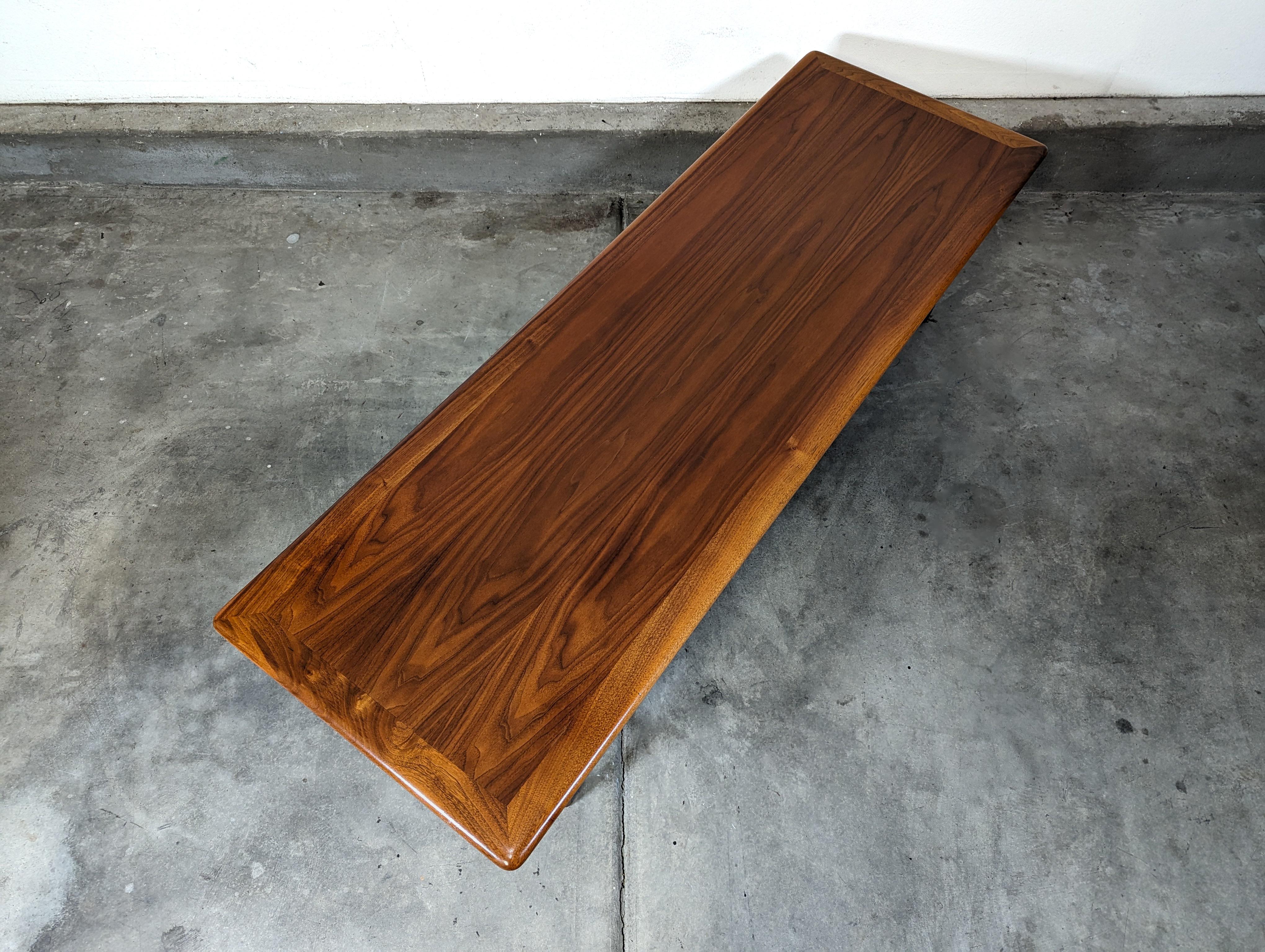 Step back in time with this exquisite vintage mid-century modern coffee table, a true gem from the 1960s crafted by Lane Furniture, a company renowned for its lasting quality and pioneering American designs. This gorgeous walnut piece has been