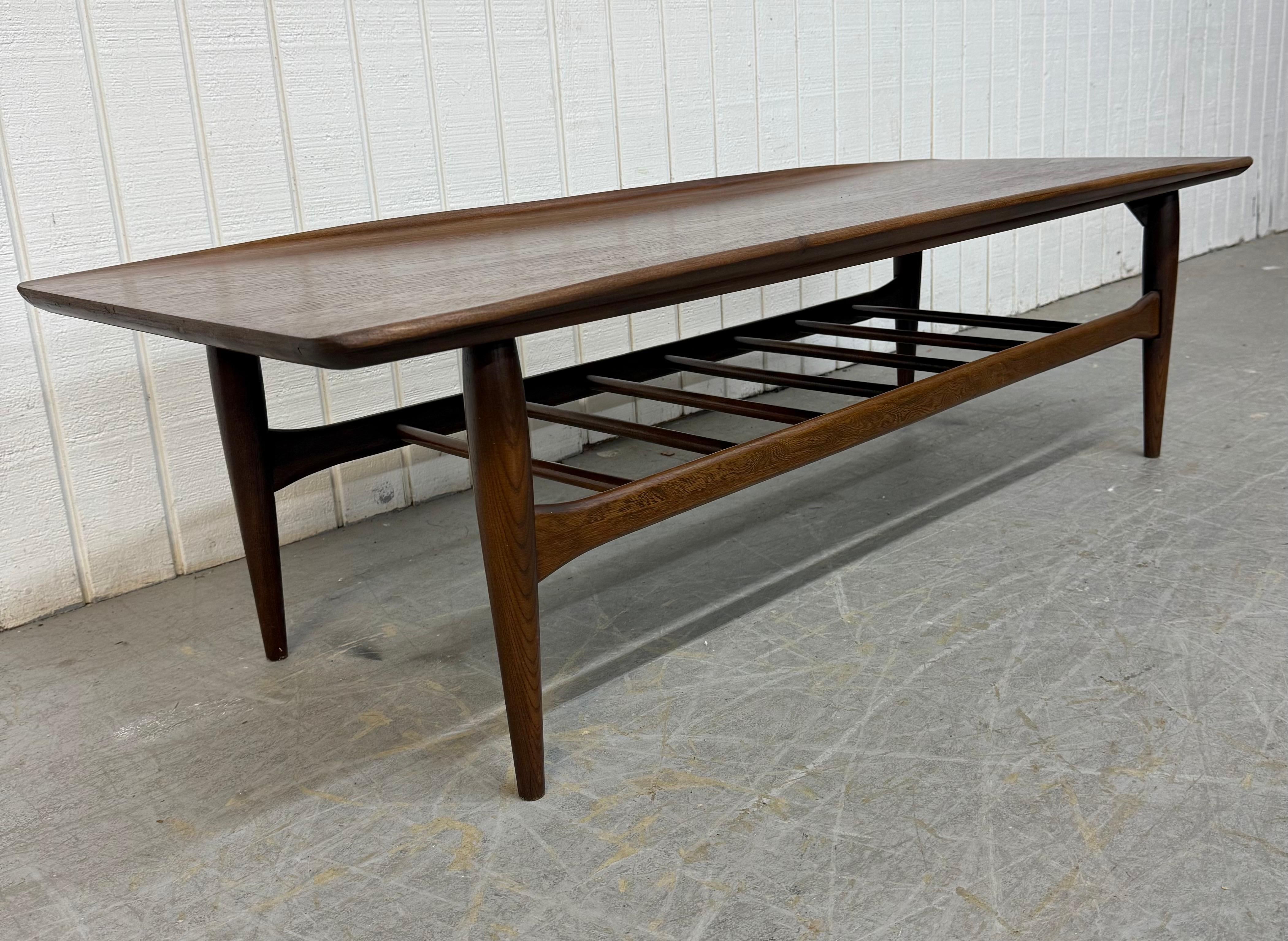 Cette annonce concerne une table basse en noyer de style moderne du milieu du siècle. Avec un design rectiligne, un plateau rectangulaire en bois, des pieds modernes, un porte-revues en forme de fuseau et une belle finition en noyer. Il s'agit d'une