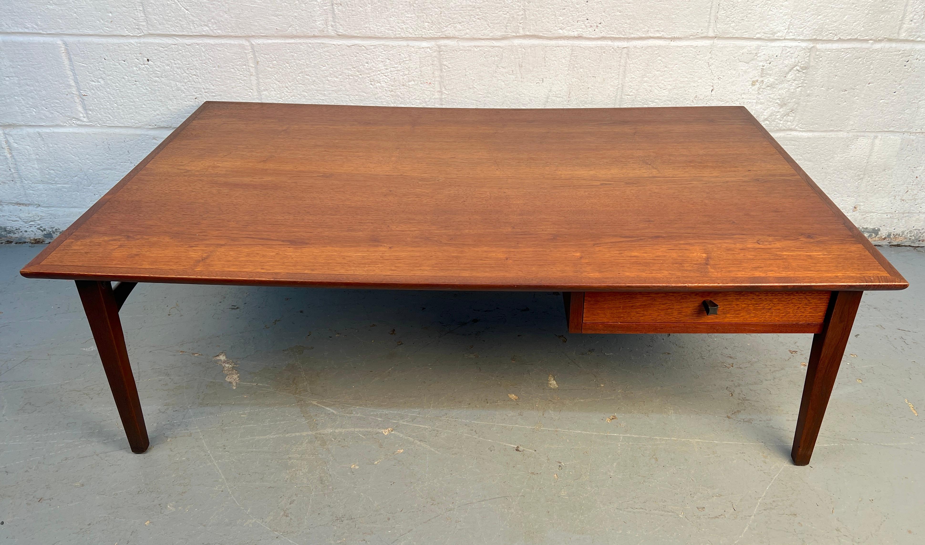 Elégante table basse moderne du milieu du siècle, fabriquée à partir de noyer au grain chaud et riche. Ses lignes épurées, ses pieds fuselés et son tiroir de rangement pratique allient un design intemporel à une fonctionnalité quotidienne pour tout