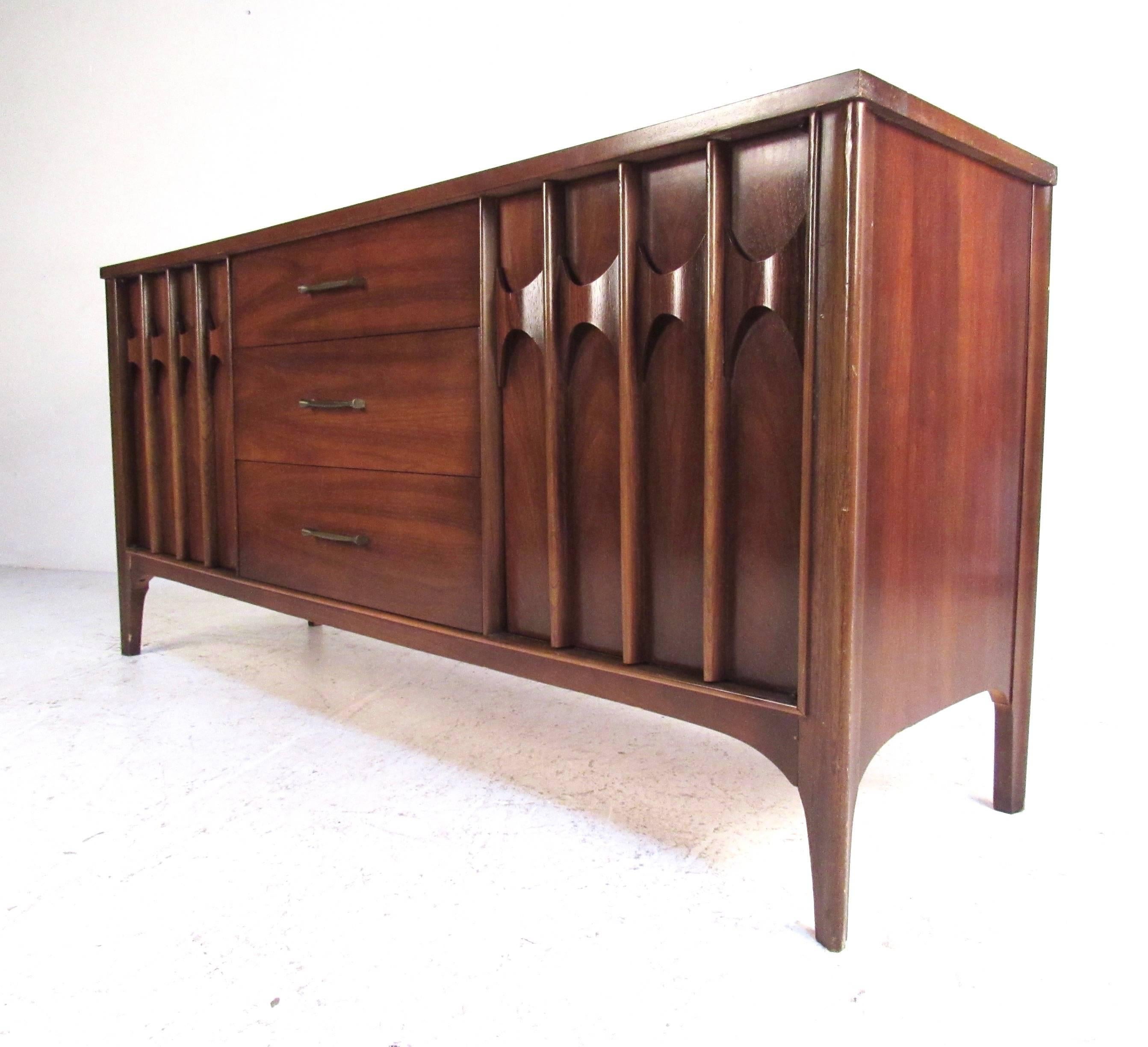 This vintage sideboard features sculpted modern door fronts, rich walnut finish, as well as a mix of interior cabinet space and drawers. Stylish mid-century credenza boasts Kent Coffey style and makes a great sideboard or credenza for dining room,