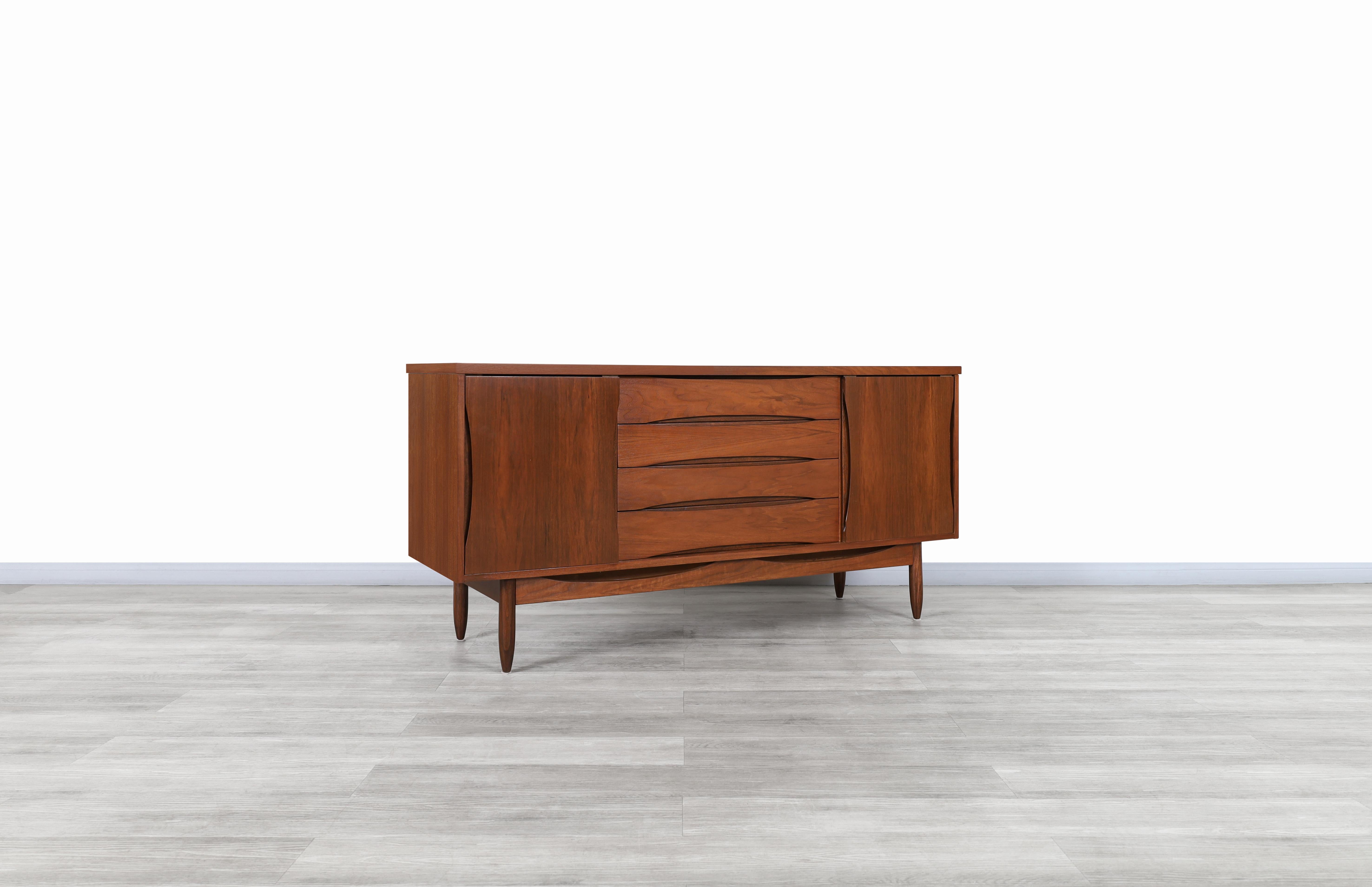 Wonderful Mid-Century Modern walnut credenza designed by Broyhill and manufactured in the United States, circa 1960s. This credenza has a modern design where the walnut wood grains give it a better contrast throughout its entire structure. Features