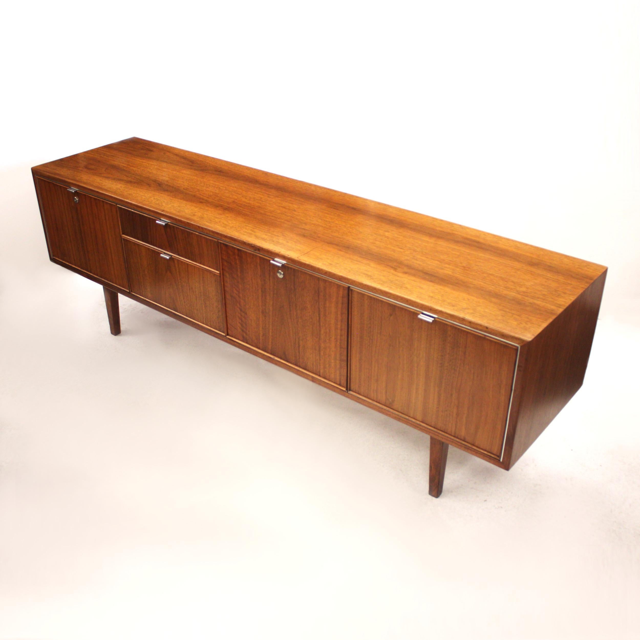 This wonderful Mid-Century Modern credenza by Stow Davis is full of unique features. With its beautifully clean lines, matched-grain veneer, and touch of polished aluminium accents, it is the epitome of 1970s chic. Stow Davis is renowned for its