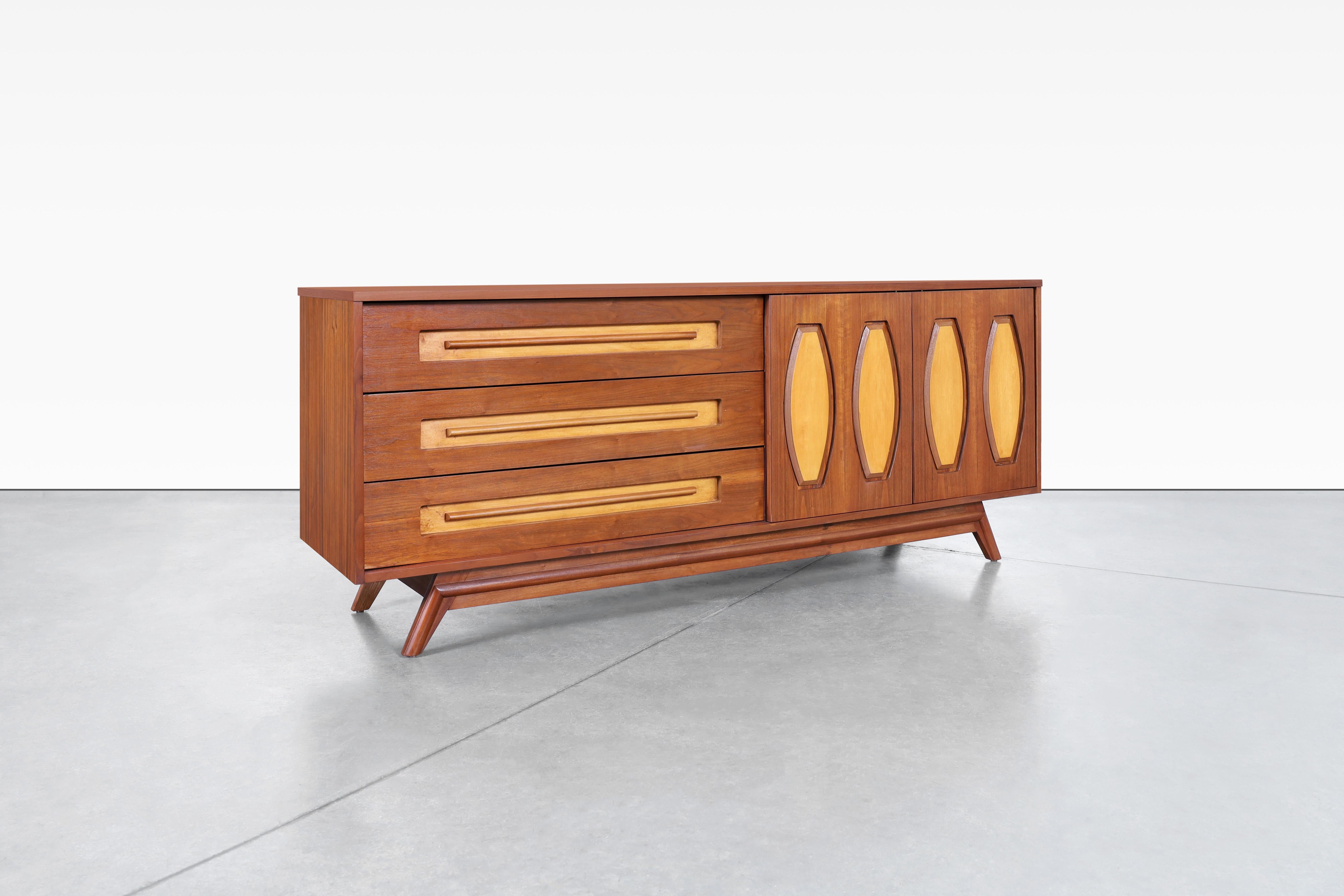 Introducing a stunning mid-century dresser designed by Young Manufacturing in the United States during the 1960s. This credenza is truly an exceptional piece from the finest quality walnut wood and birch; the natural grain patterns of the wood