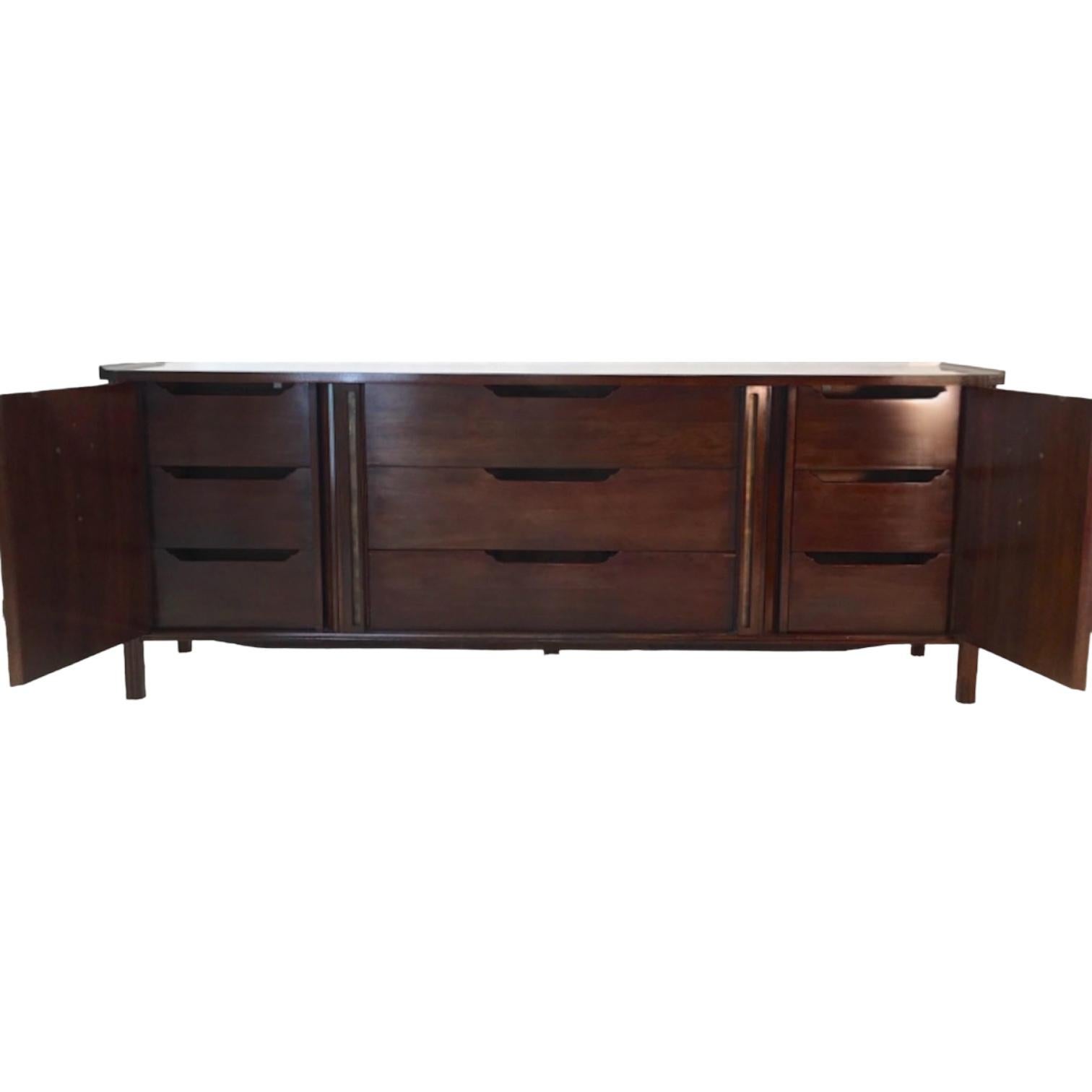 This is a beautiful mid-century modern sleek walnut chest designed by Bert England for John Widdicomb’s Orientation Group. The center tabour doors slide to reveal three more drawers, bringing the drawer total to nine. It is marked. The hardware is a