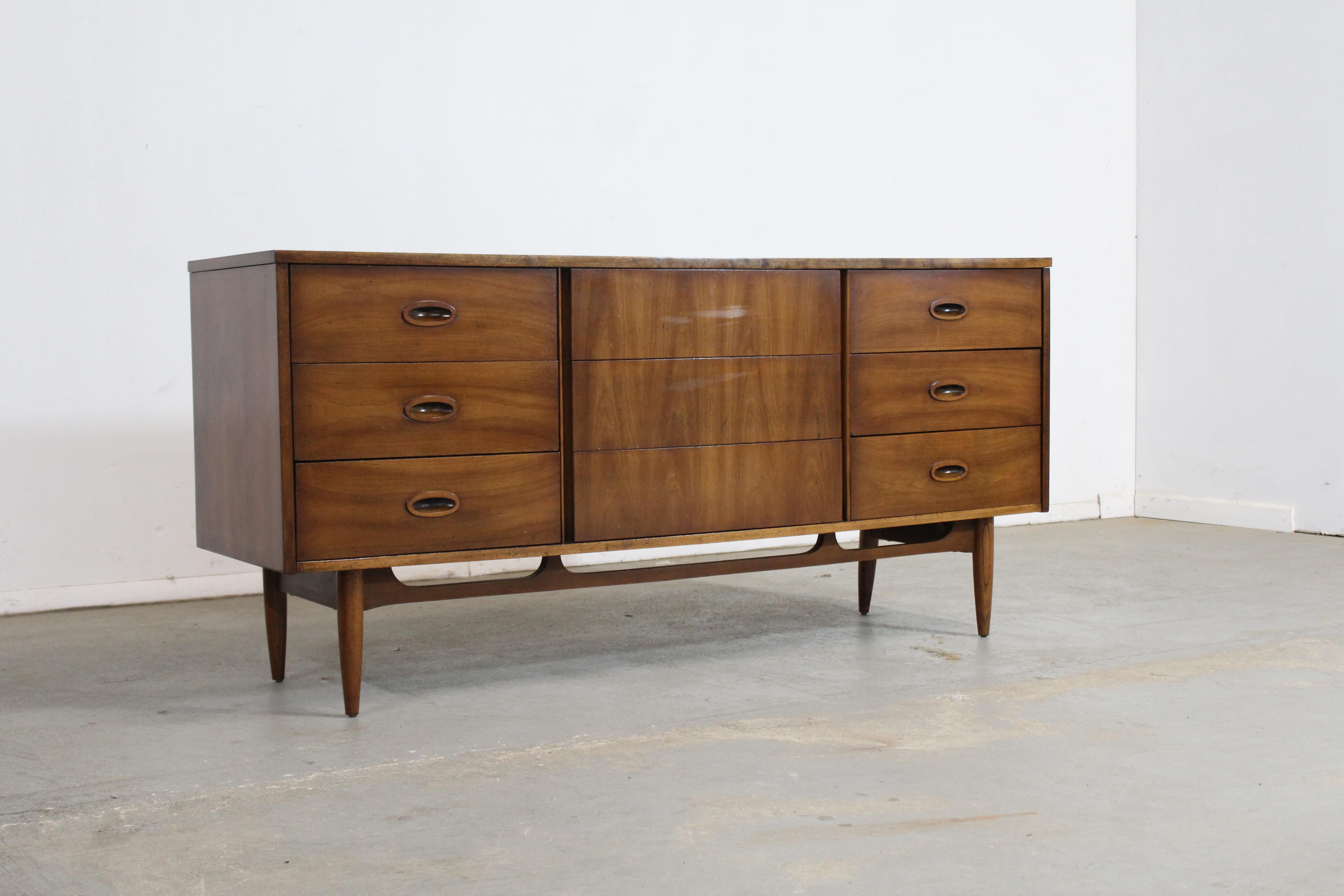 Mid-Century Modern walnut credenza/dresser on pencil legs.

Offered is a beautiful Mid-Century Modern walnut credenza/dresser with ample storage space, which was manufactured by Dixie. The Credenza has a wonderful stretcher base and is elevated on