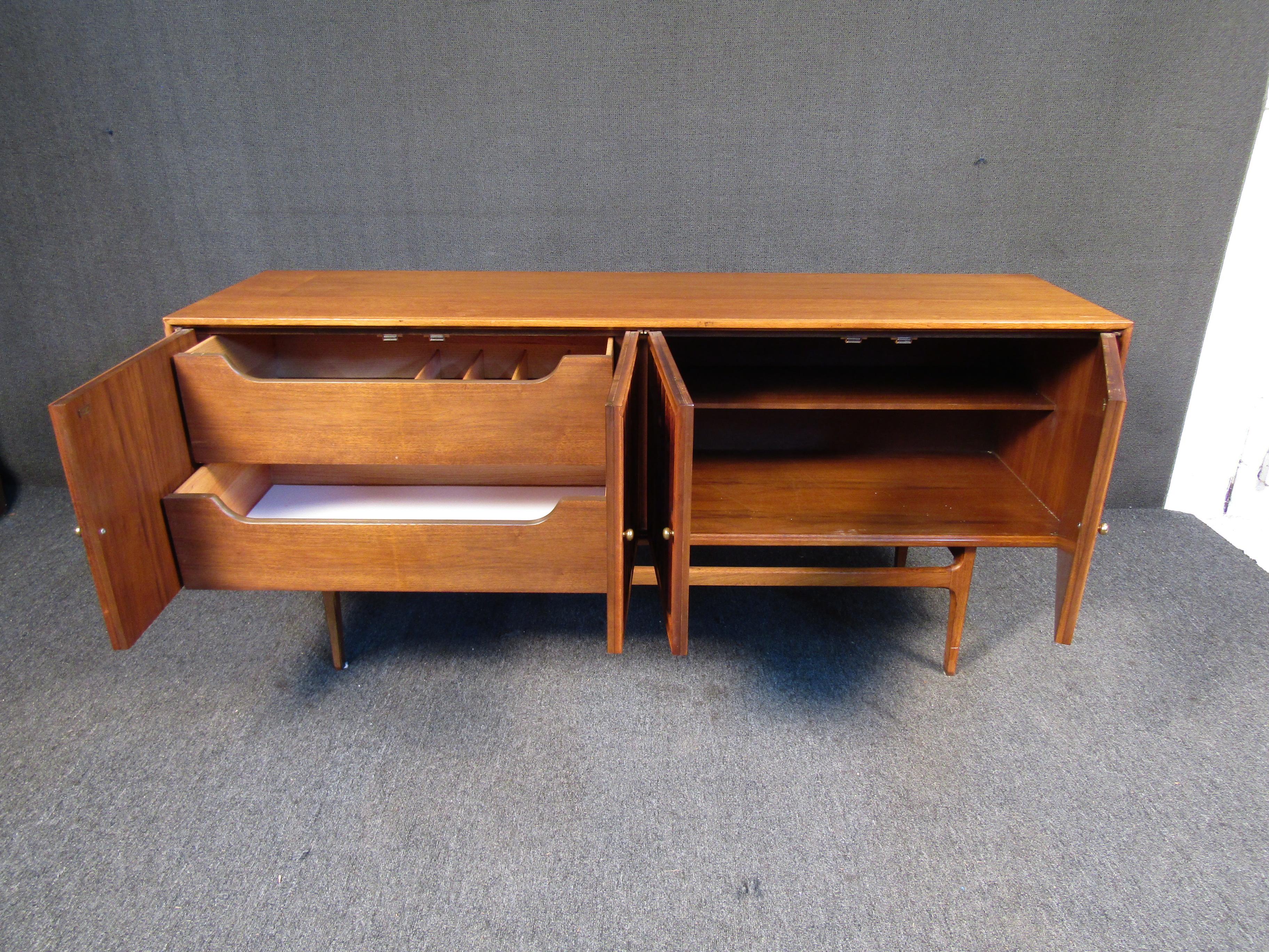This Mid-Century Modern credenza features a unique front design, tapered legs and light walnut finish. The credenza also has two drawers and shelving offering adequate storage space. A beautiful addition to any home.


Please confirm item