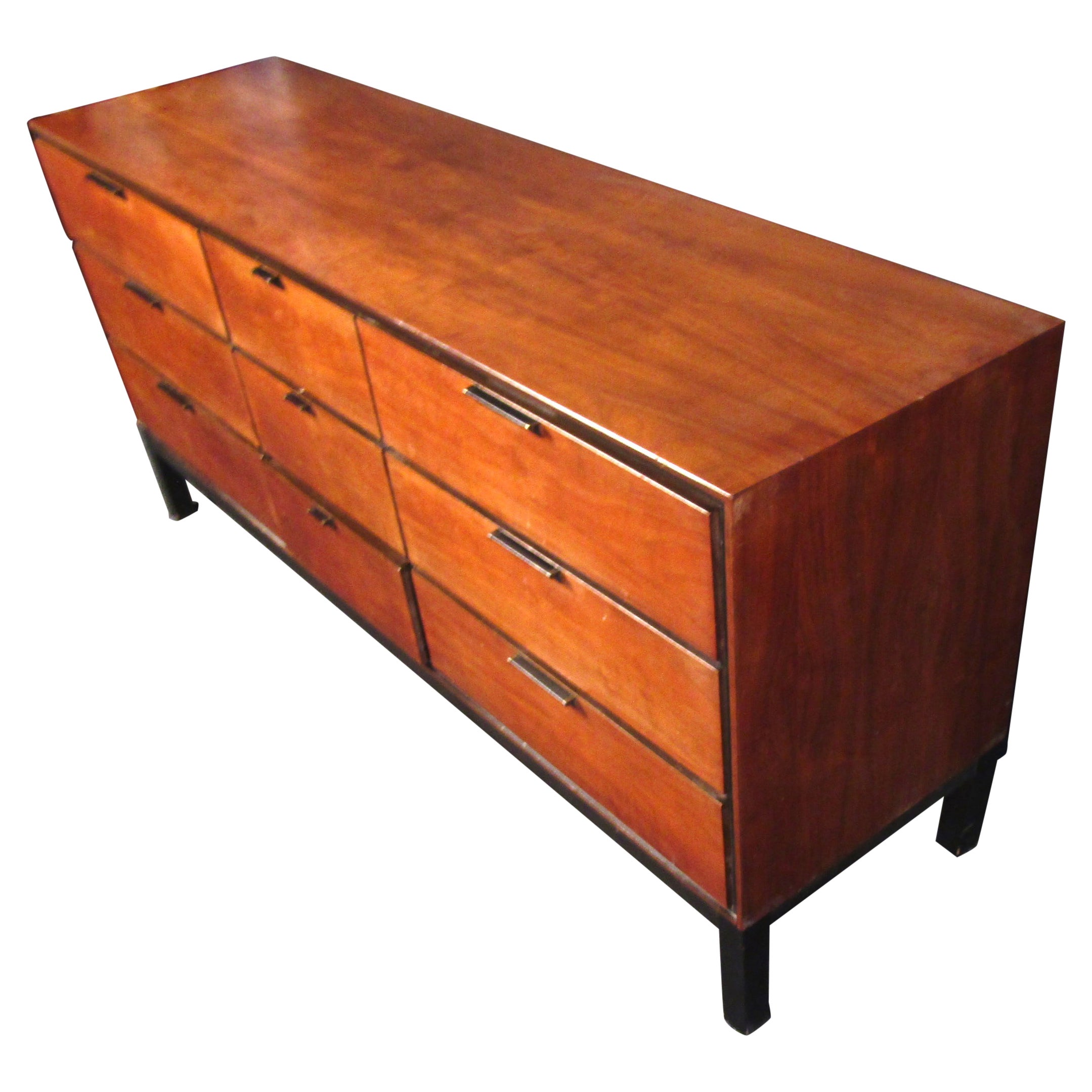 Precioso aparador vintage moderno de nogal. Este aparador cuenta con nueve espaciosos cajones, siendo más largos los de los lados izquierdo y derecho, y más cortos los del centro. Los cajones están equipados con bonitos herrajes negros y metálicos.