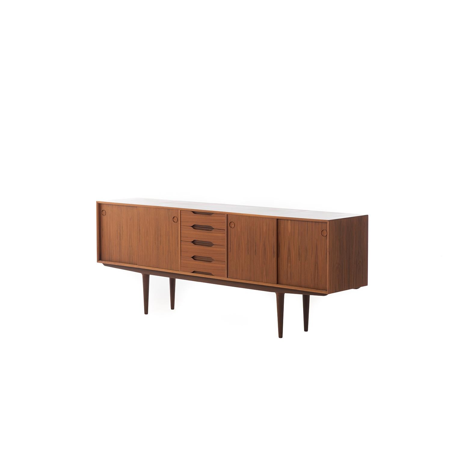 Mid-Century Modern walnut credenza with sliding doors. Features adjustable shelves and four silver drawers.