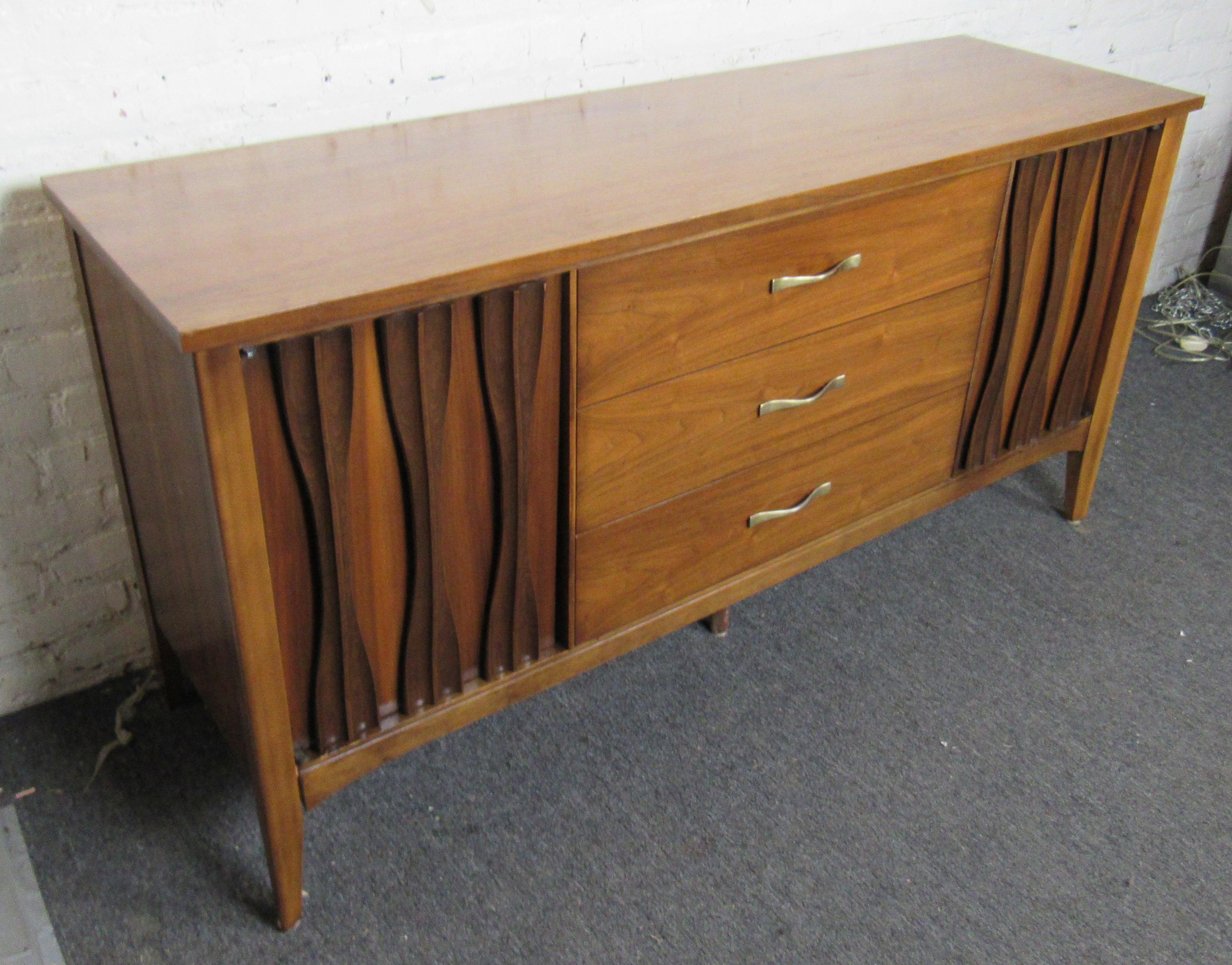 Beautiful vintage modern American made walnut wood credenza. This stunning credenza features three spacious center drawers with metal pulls, to the left and right side are two spacious cabinets with one shelf each. The cabinet doors have beautiful