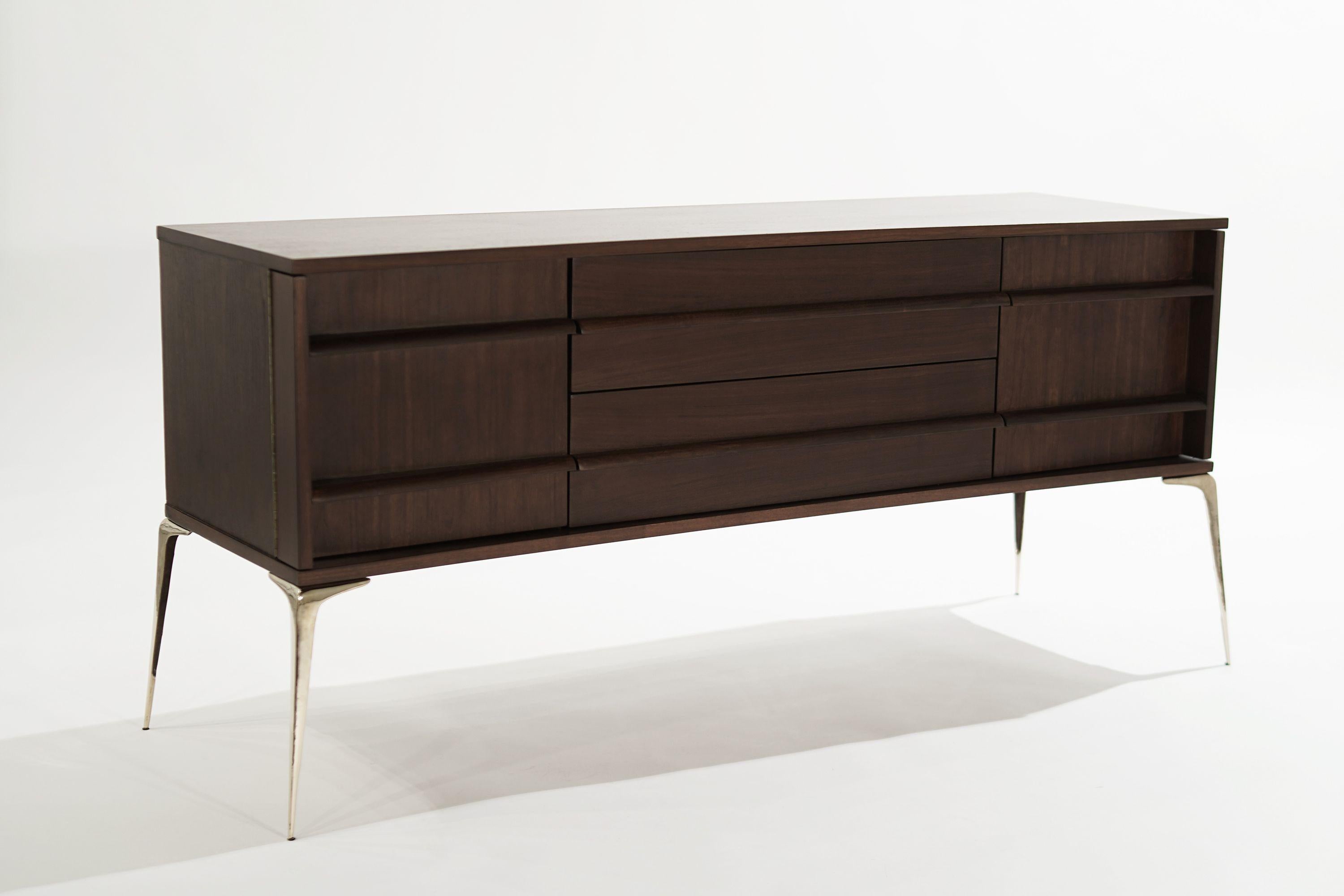A Mid-Century Modern credenza executed in walnut, featuring brass 