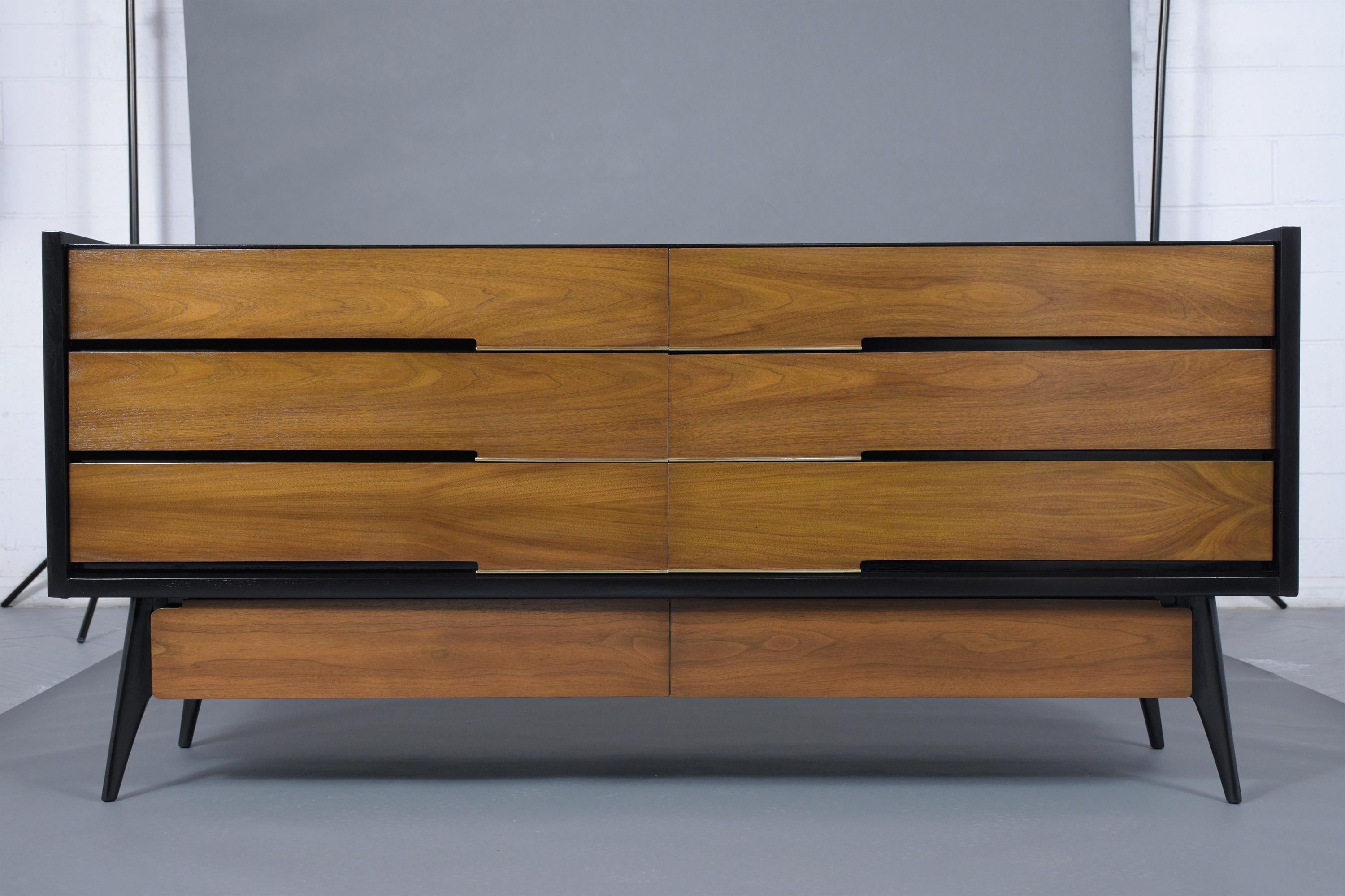 A mid-century 1960's Credenza crafted out of walnut wood, this fabulous piece has been professionally restored and has been newly stained and ebonized & walnut color combination with a lacquer finish. This Chest of Drawers features plenty of