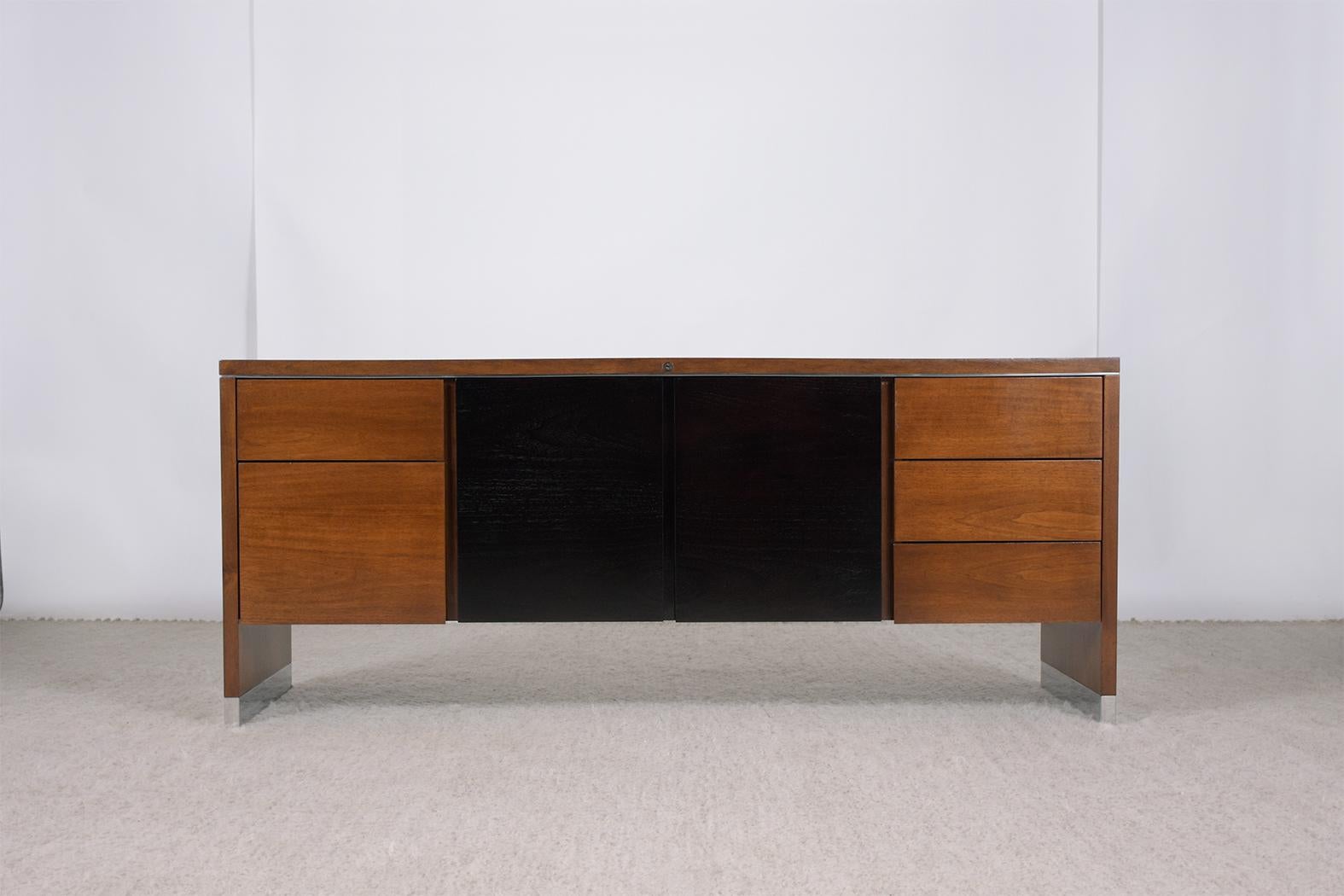 This Mid-Century Modern credenza is crafted out of mahogany is in good condition and has been professionally restored by our team of craftsmen. The dresser has been newly stained in mahogany & ebonized color combination with a lacquered finish comes
