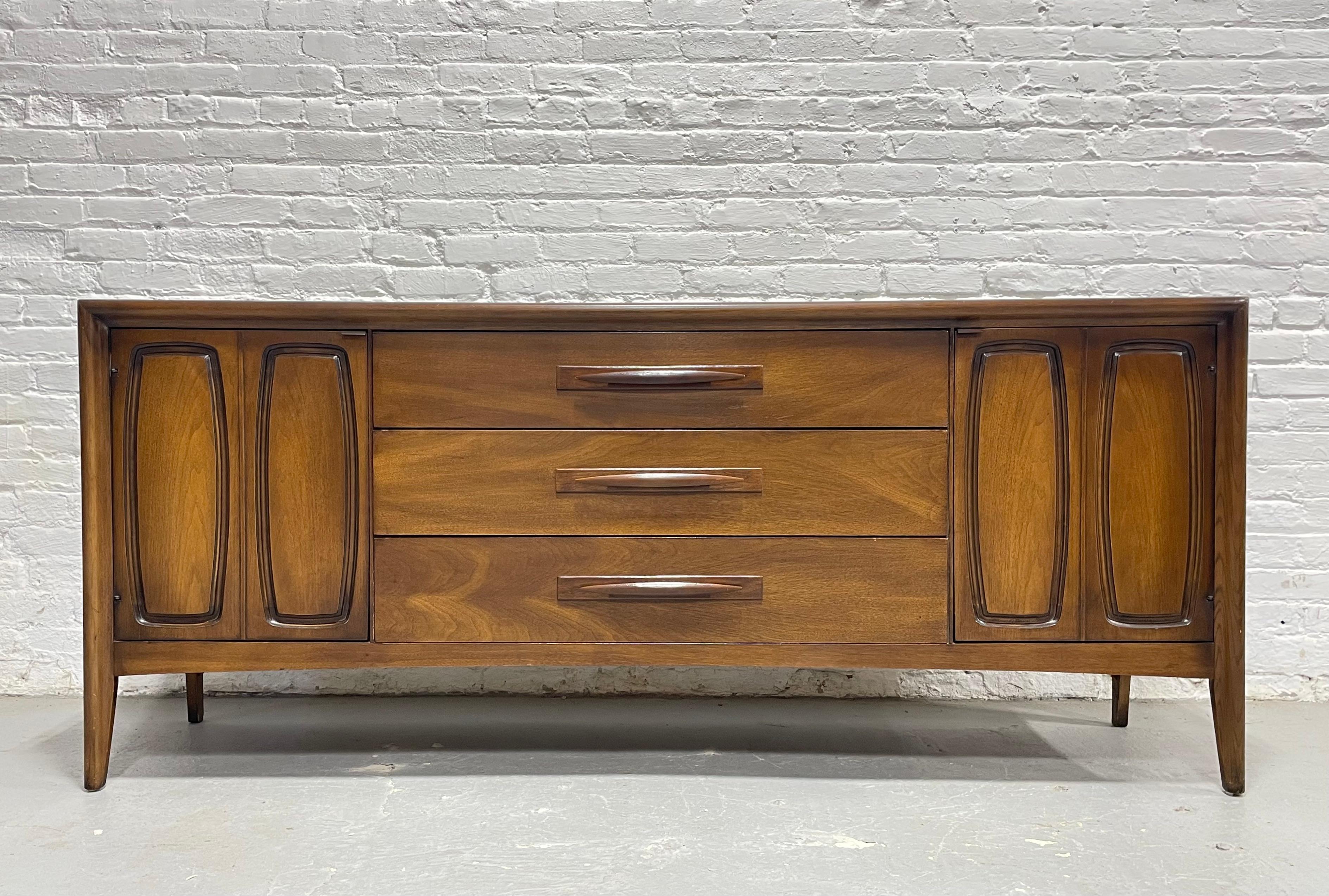 Walnut Mid Century Modern Credenza Dresser by Broyhill Premier, c. 1960's.  Boasting gorgeous wood grains, this long dresser is a powerhouse when it comes to storage, offering three deep and spacious doors at the center and an additional three