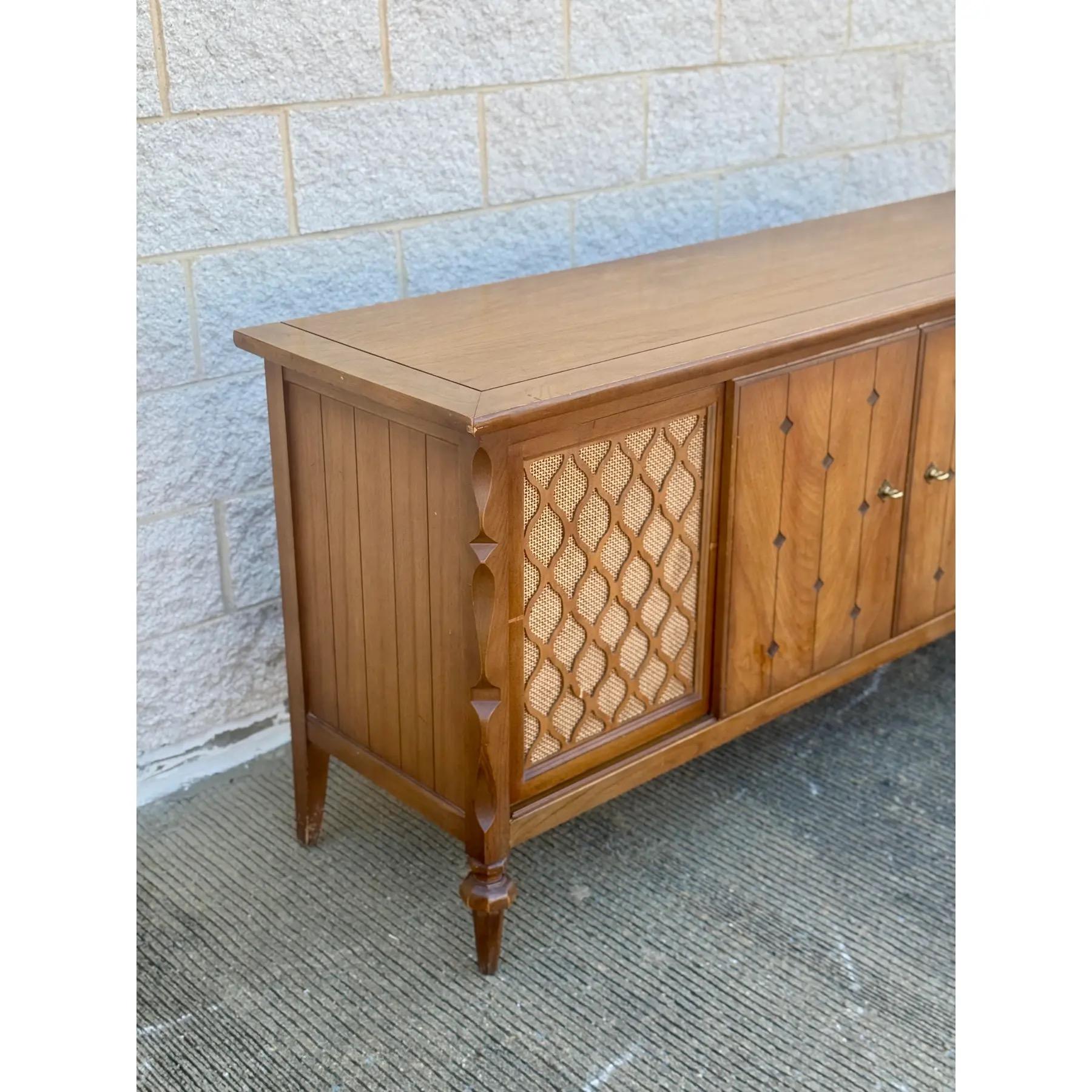 Stunning mid-century modern credenza blends timeless elegance with warm character. Crafted from rich walnut wood, it features two outer cabinet doors with sculpted diamond-patterned cane inserts and four central paneled doors with delicate diamond